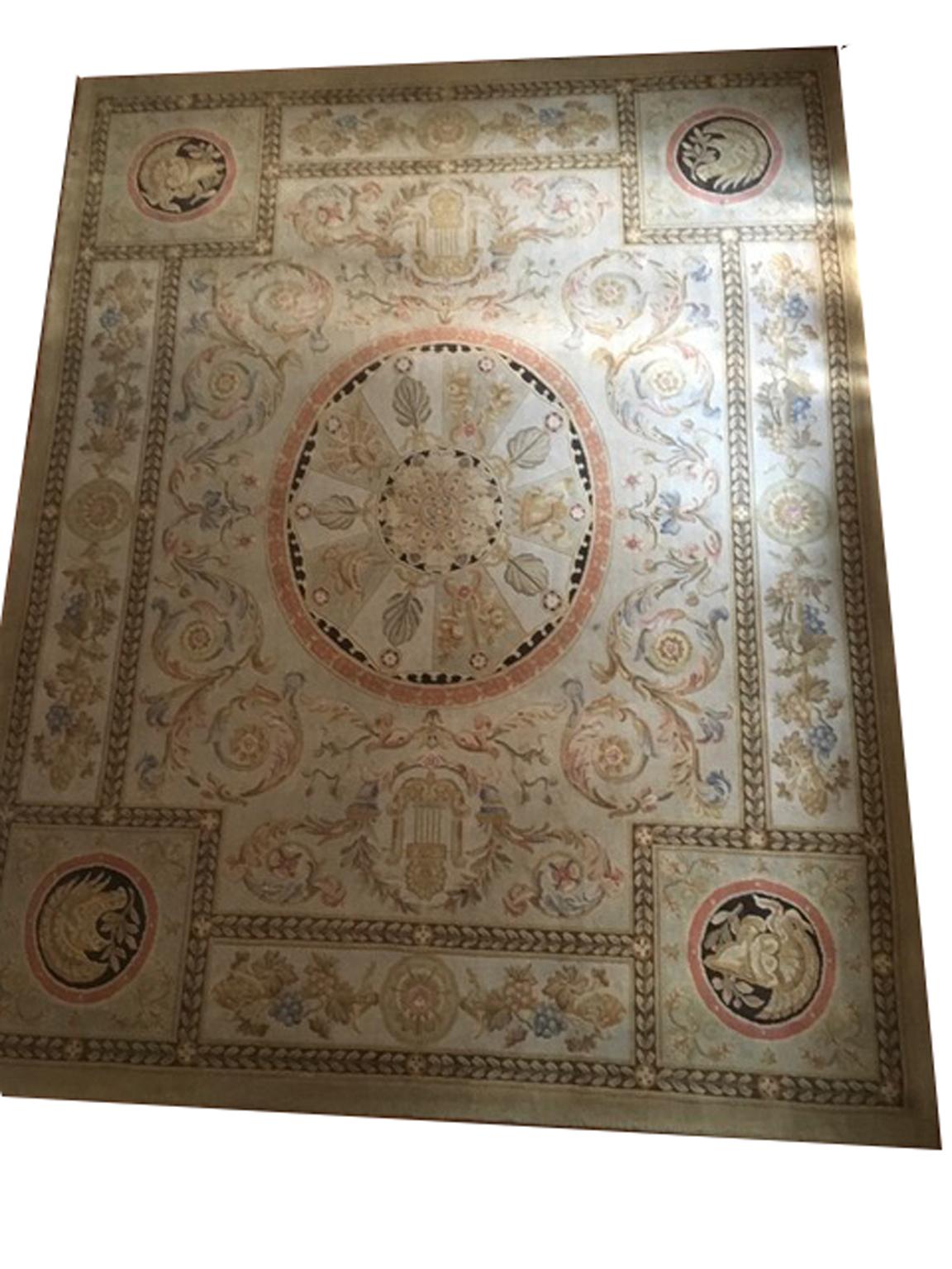 This Mid-Century French wool rug has been manufactured in France in circa 1960 in the French neoclassical style, called Savonnerie. The central medallion is typical of French Empire style. The pastel colors of flower's bunches, like orange, ecru',