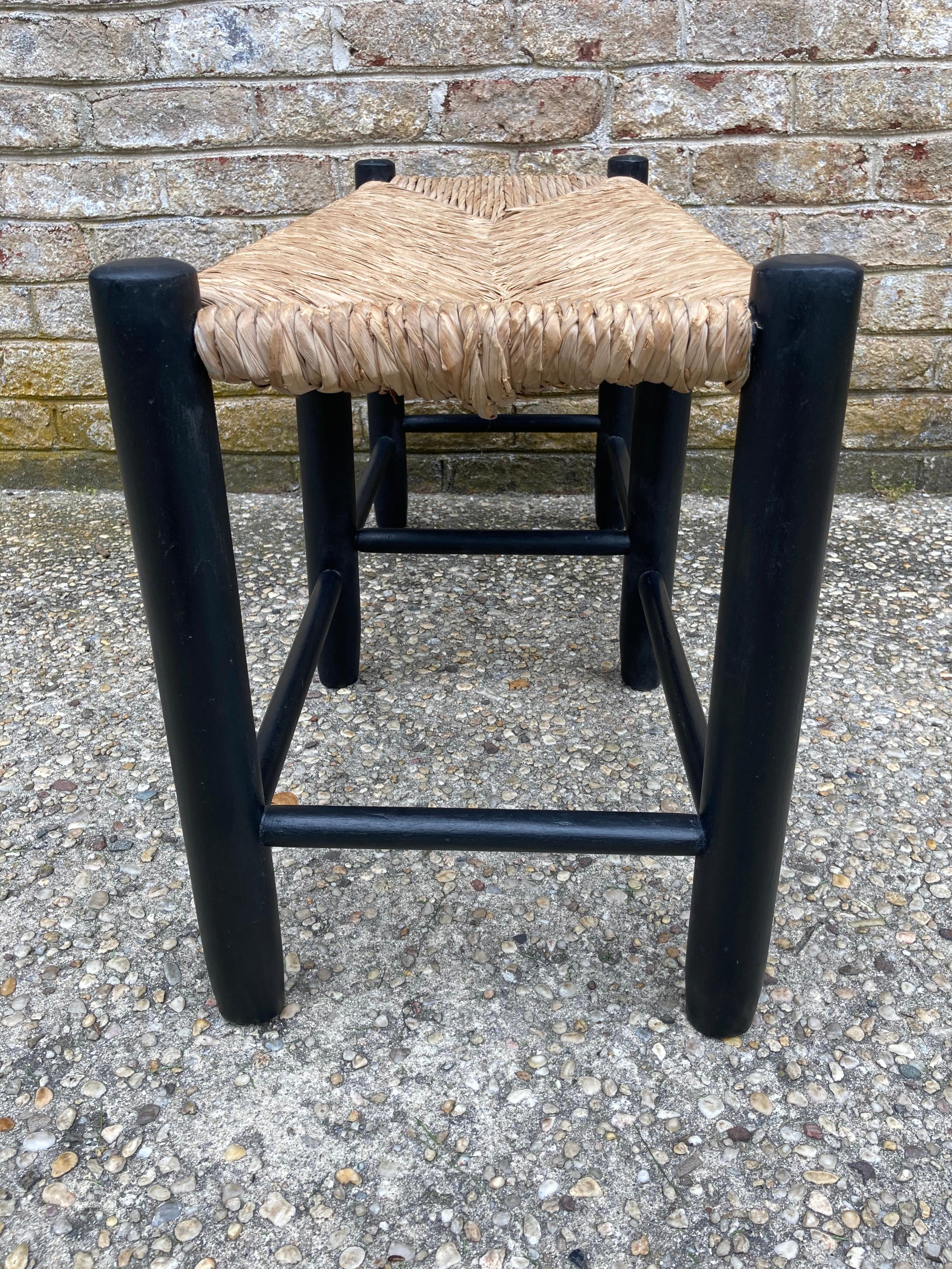 Ebonized wood bench with rush seat in the style of Charlotte Perriand....