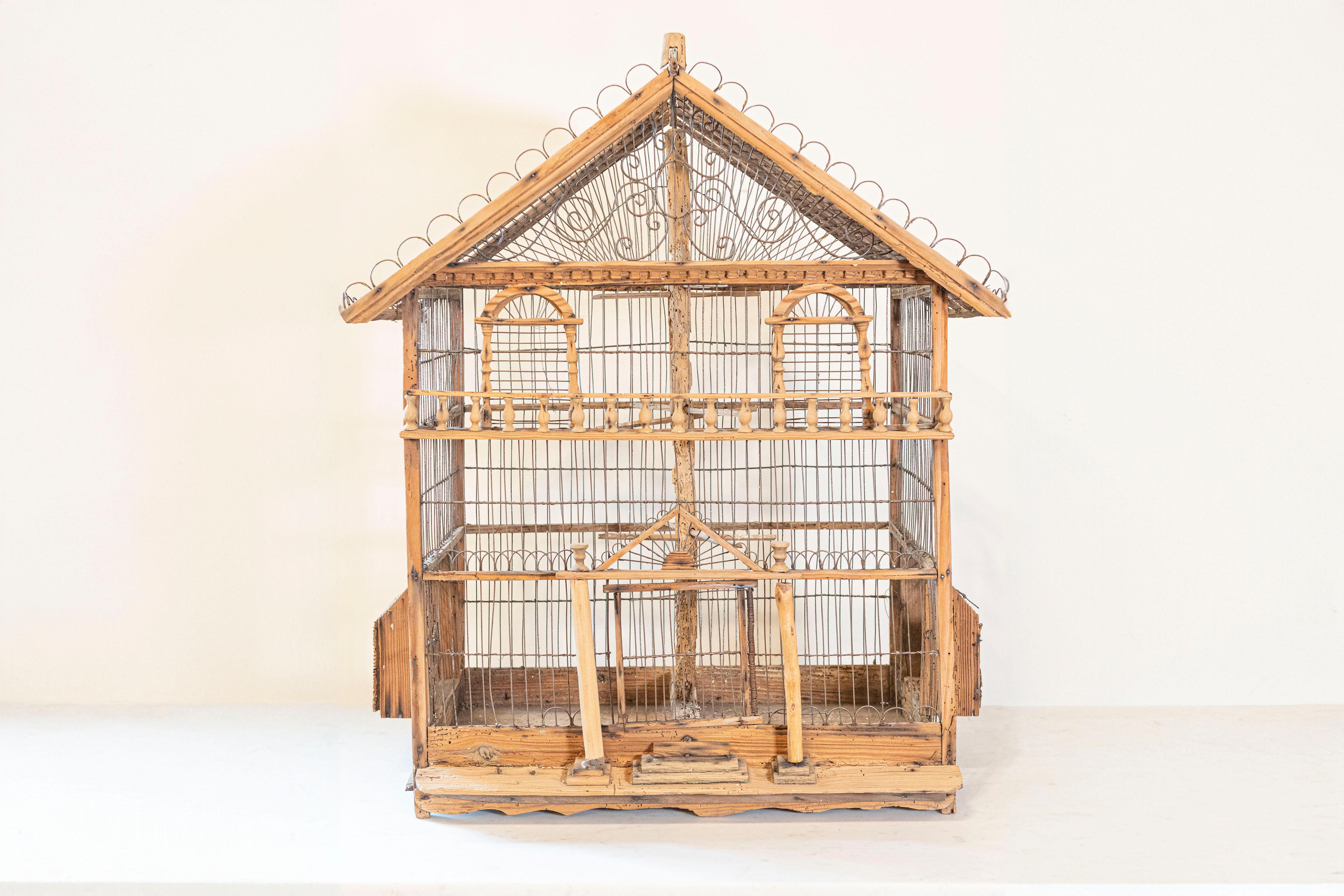 A French rustic Napoléon III period wooden birdcage from the mid 19th century, with scrolling metal accents and baluster motifs. Created in France during the third quarter of the 19th century, this wooden birdcage, shaped as an elegant house, is