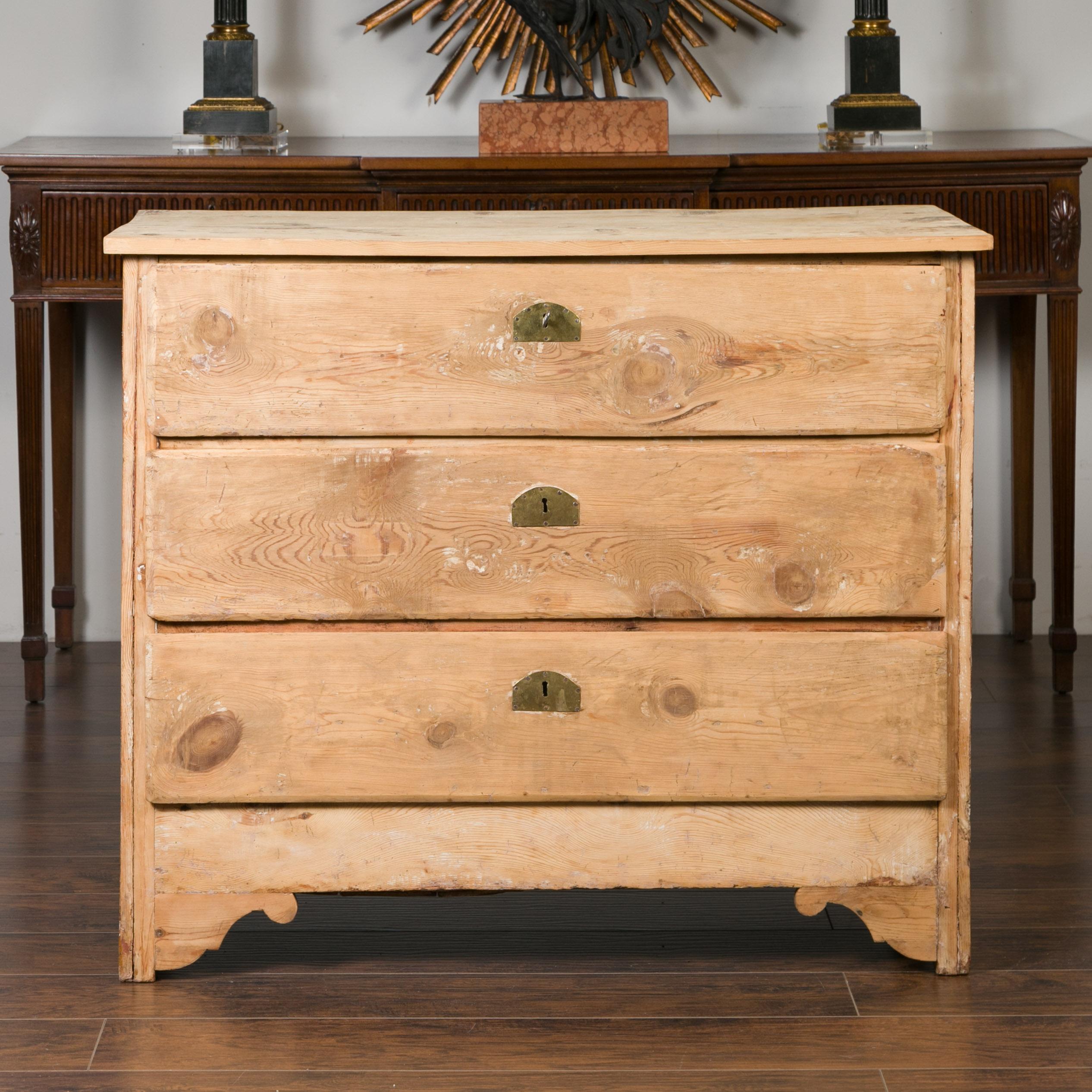 A French bleached pine three-drawer commode from the late 19th century, with carved spandrels. Created in France during the 19th century, this newly bleached chest features a rectangular planked top sitting above three drawers fitted with brass