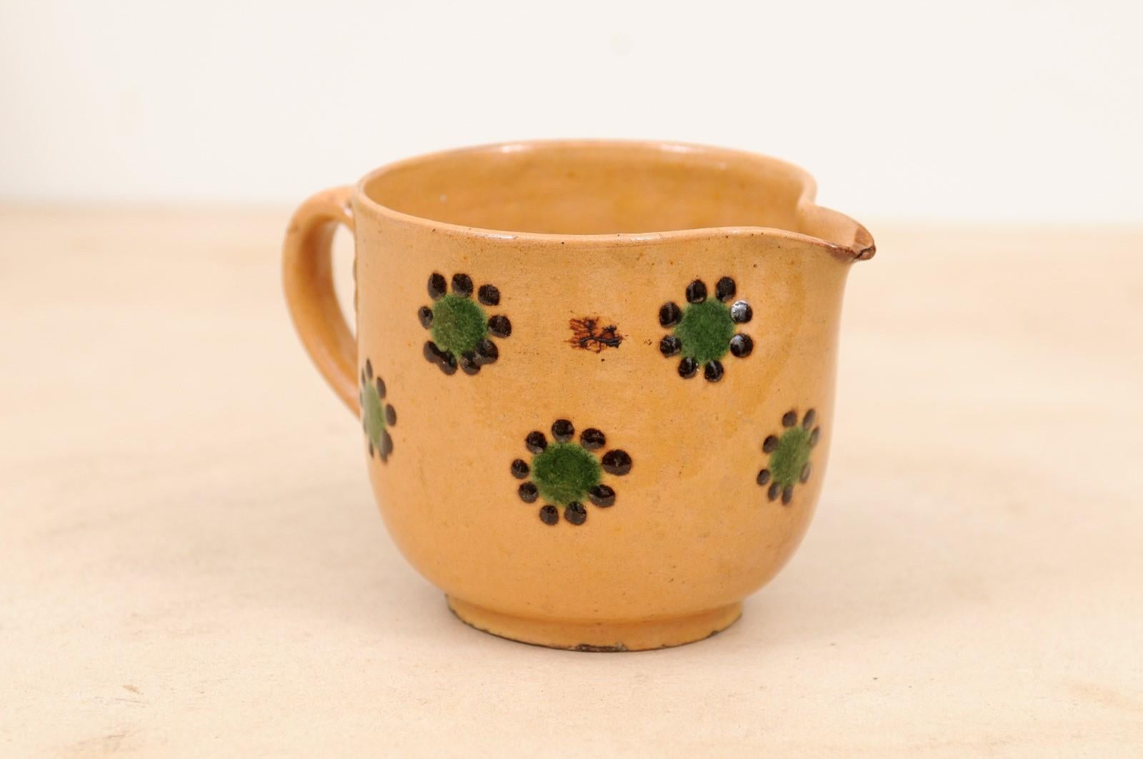 A French pottery pitcher from the 19th century, with peach glaze accented with green and chocolate décor. Created in France during the 19th century, this rustic pitcher features a peach colored ground perfectly highlighted by green and chocolate
