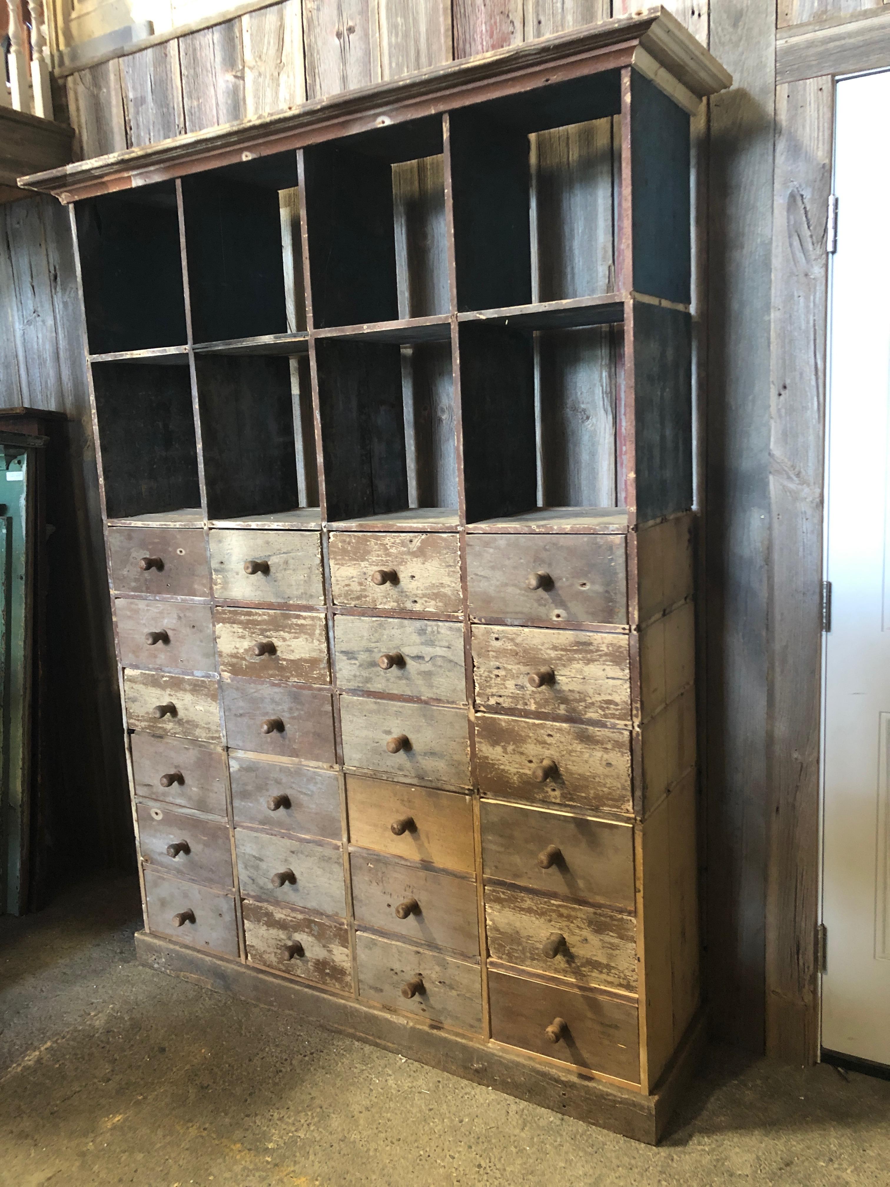 Found in Le Mans France, this is a one of a kind hand crafted multi drawer and cubbie cabinet having 24 individual drawers on bottom half and 8 open cubbies on the upper section. Cubbies are 14 D x 13 W.
The wood is old and reclaimed with a lively