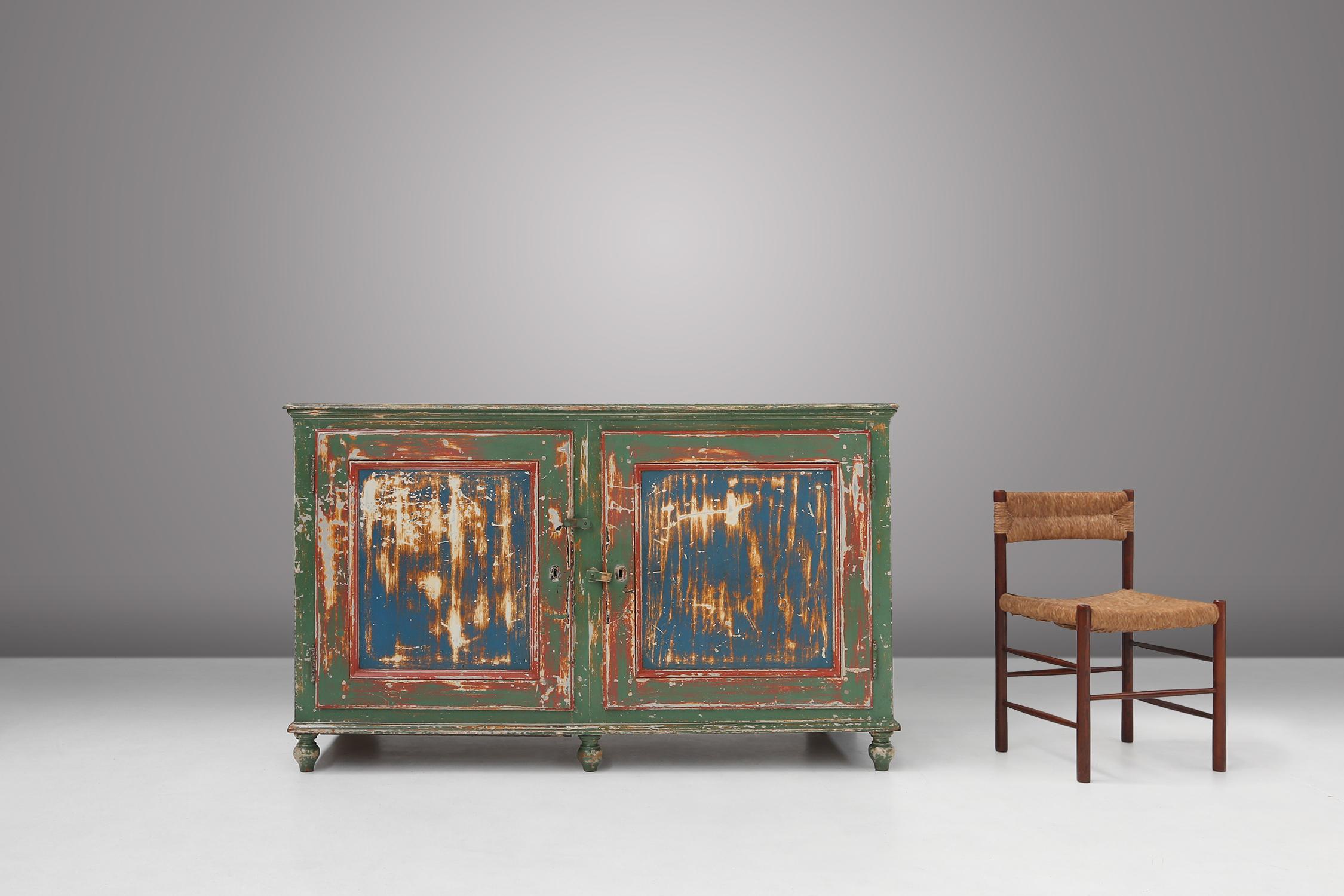 
This cabinet made in the 1920s is painted in a beautiful green with ee, which creates a rustic and cosy atmosphere. The doors are painted blue and red with a weathered finish, which gives the cabinet an authentic and rustic look.

The cabinet has