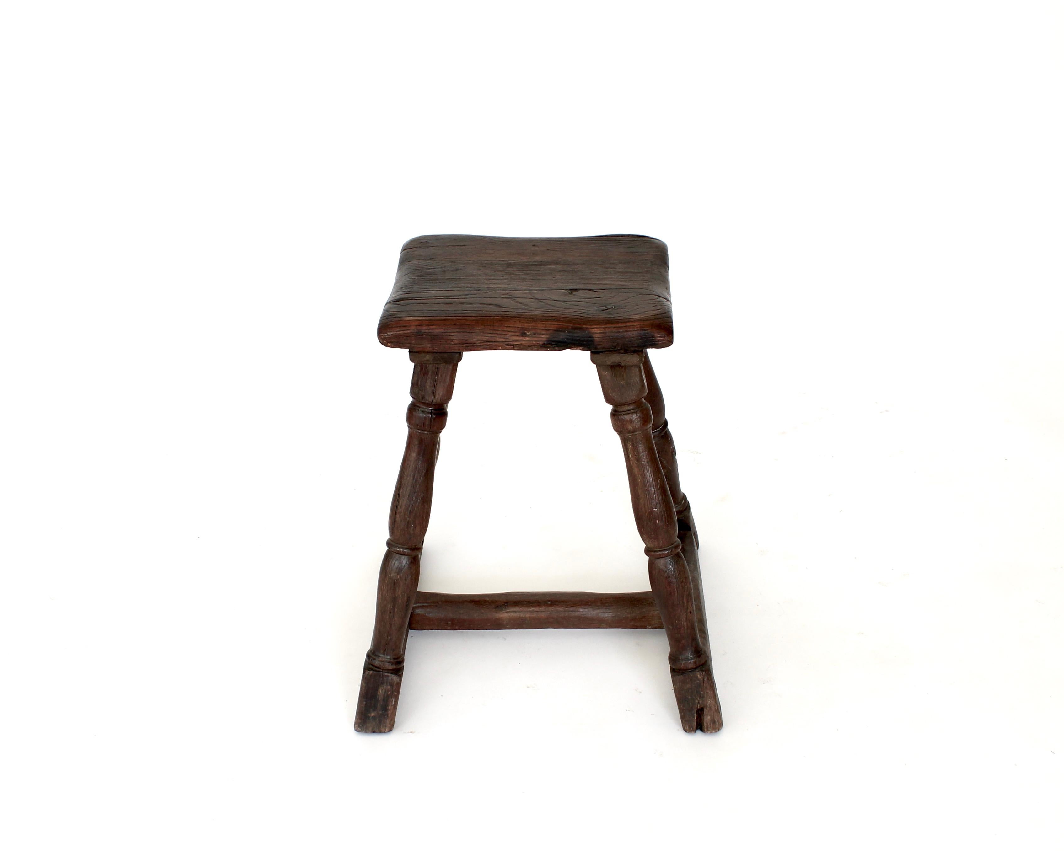 French hand made rustic stool of chestnut wood with a dark patina from age, use and care. The stool being hand made and is created without the use of nails and with only wood pegs as is normal from the time period.
The seat is 11.5