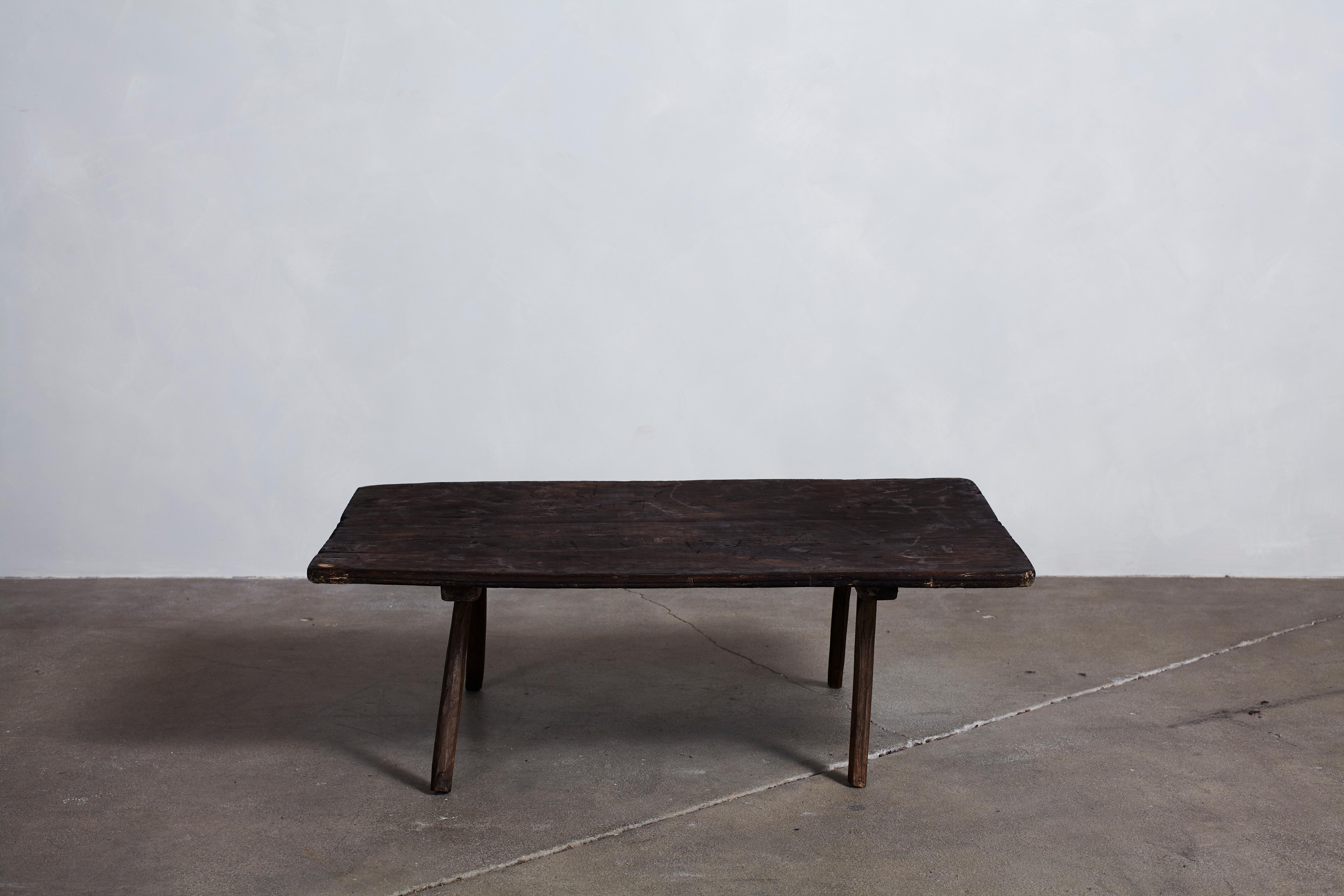 French rustic dark wooden low table with four legs.