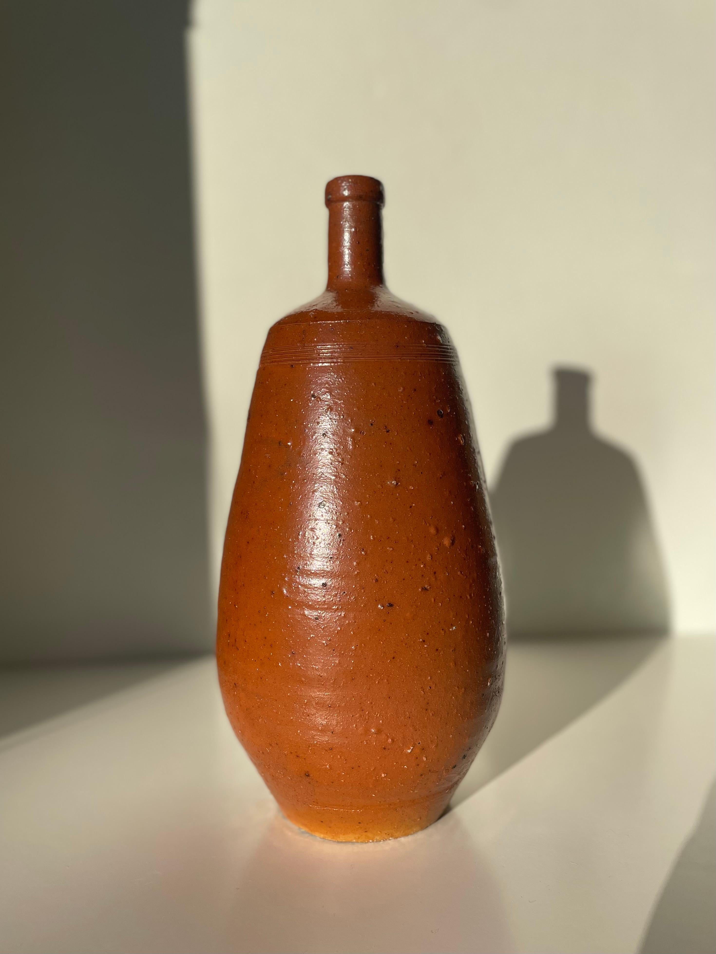 Rustic French ceramic bottle vase with warm caramel and burnt umber colored glaze. Fine horisontal lines around the neck. Great vintage condition. 
France, circa 1930s. 