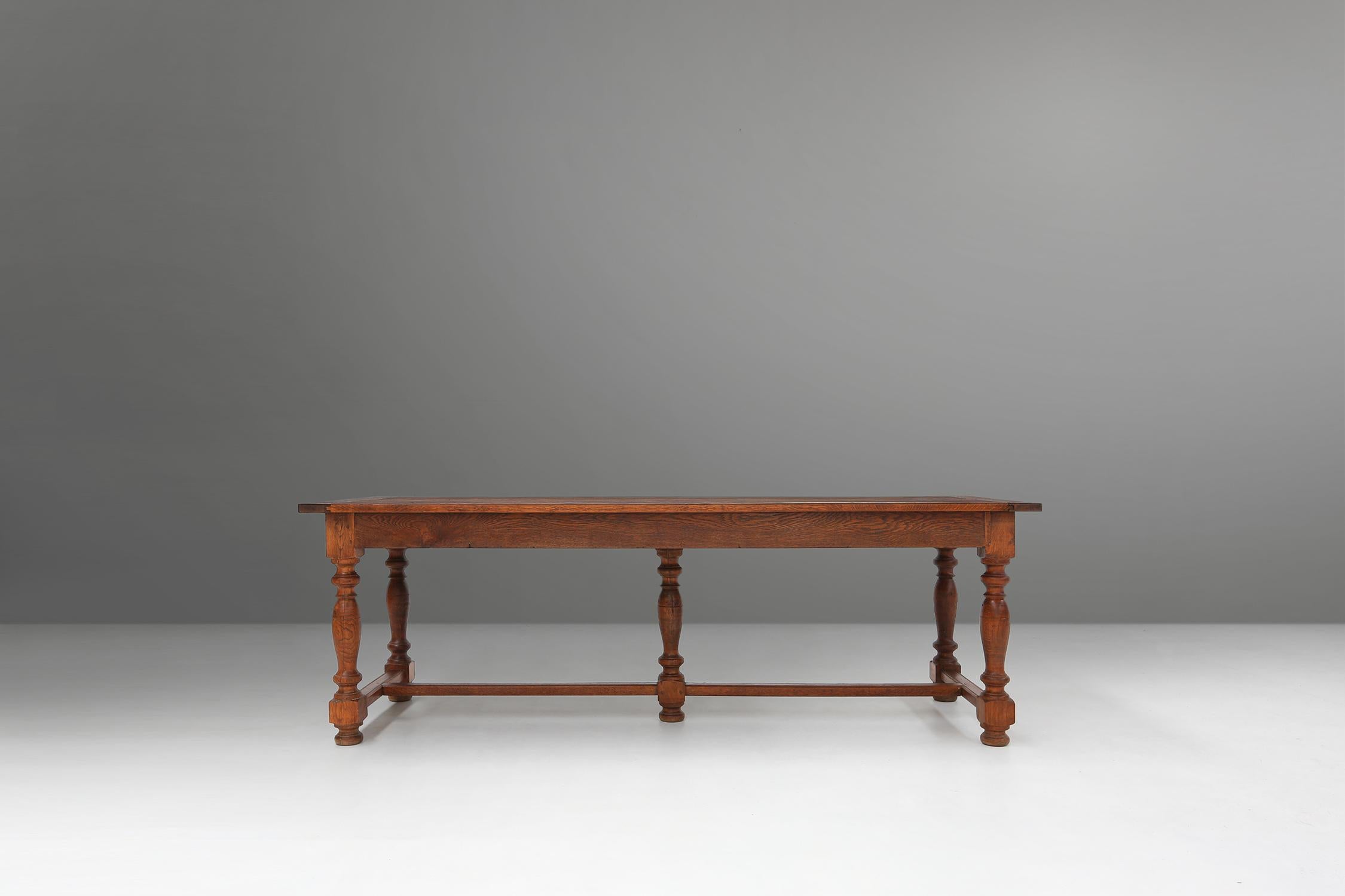 This table is made circa 1930s of solid oak and has a beautiful brown finish. The table has a rectangular top and five turned legs with spherical details. There are two drawers on either side of the table, where you can store your cutlery or other