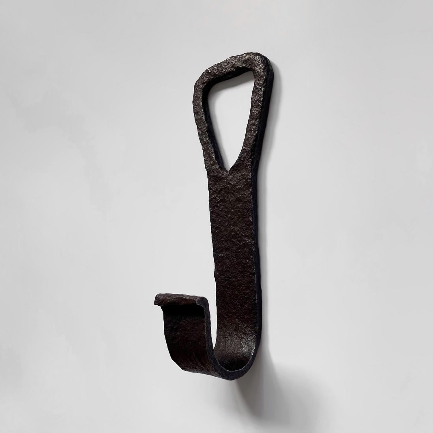 French rustic textured iron wall hook
France, mid century
Beautifully textured flat bar iron in a dark chocolate tone gives a wonderful rustic feel
Curved wide lip J hook with upturned lip detail
Nabla shaped cut out makes it easy for wall mounting