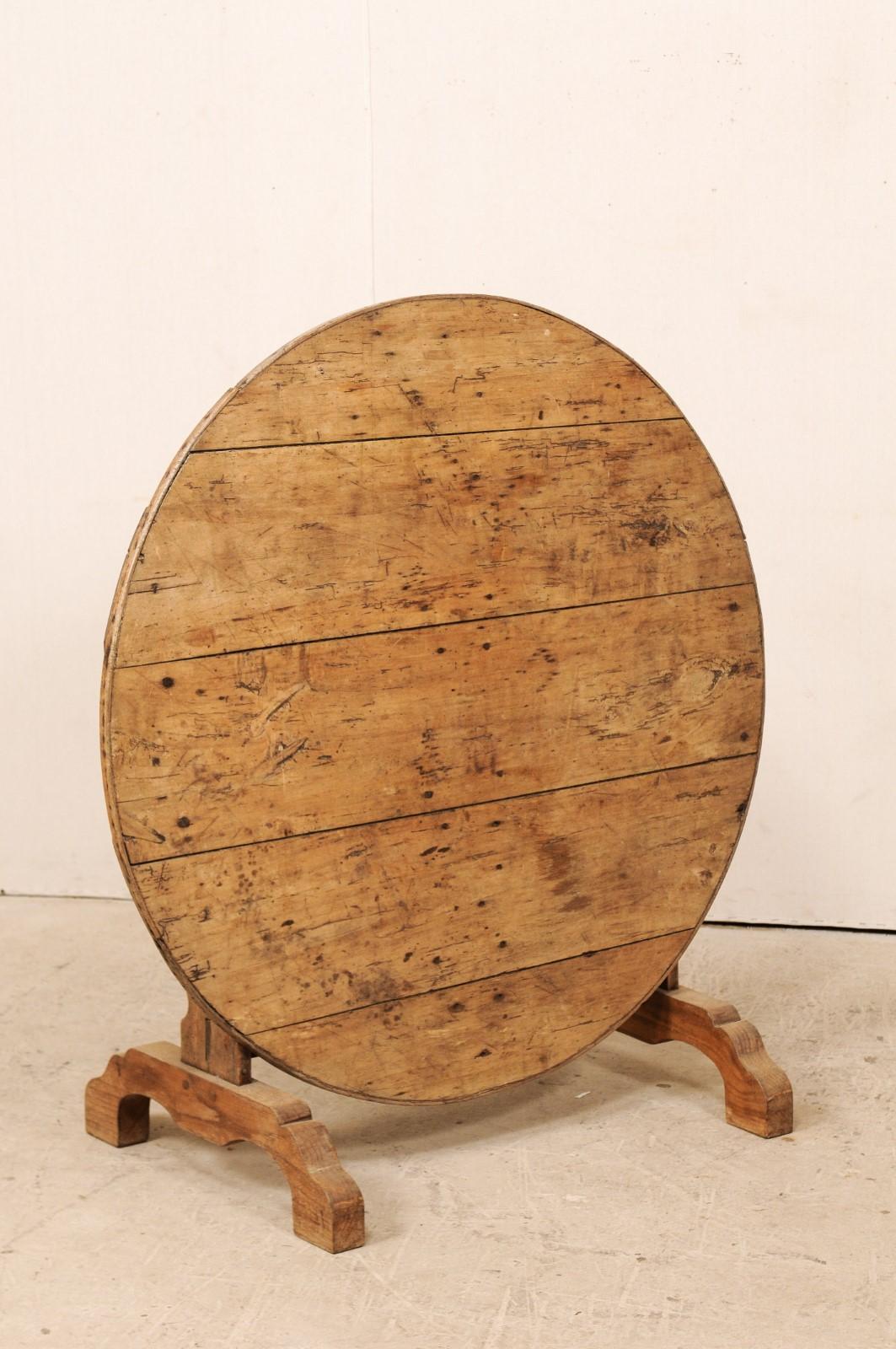 A vintage French vintner's wine tasting table. This French wine tasting table has the typical tilt top, and butterfly wedge support. The table is nicely raised and supported by its trestle base and thickly carved legs. The wood is a beautiful light