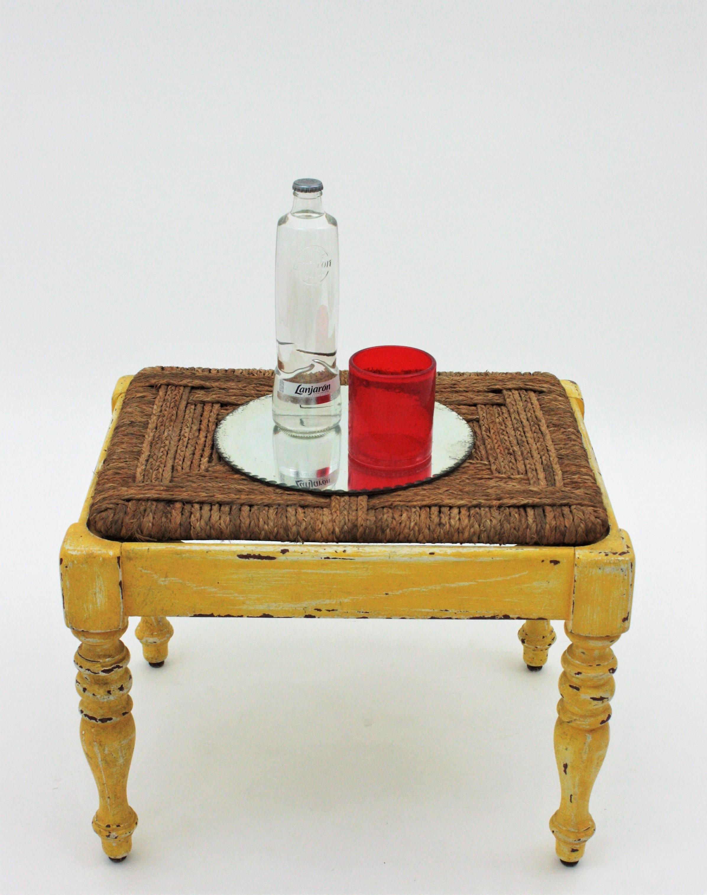 One of a kind turned wood stool in yellow patina with straw esparto grass woven seat, France, 1930s.
This rustic stool has a wooden structure with turned legs and an aged distressed patina in yellow and white. The seat is made with hand braided
