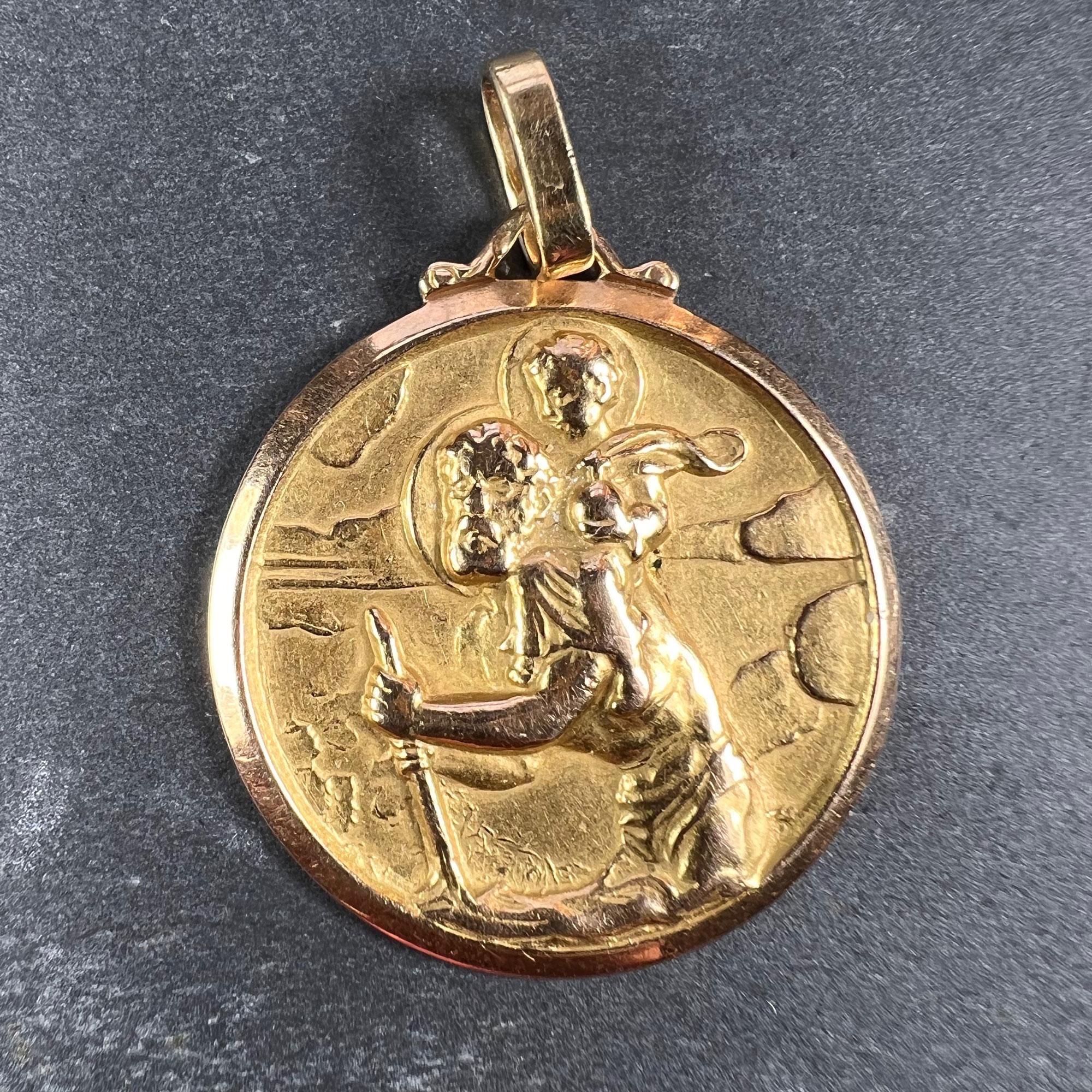 A French 18 karat (18K) yellow gold charm pendant designed as a medal depicting Saint Christopher carrying the infant Christ over the river. Stamped with the eagle mark for 18 karat gold and French manufacture.  

Dimensions: 2.8 x 2.6 x 0.2 cm (not