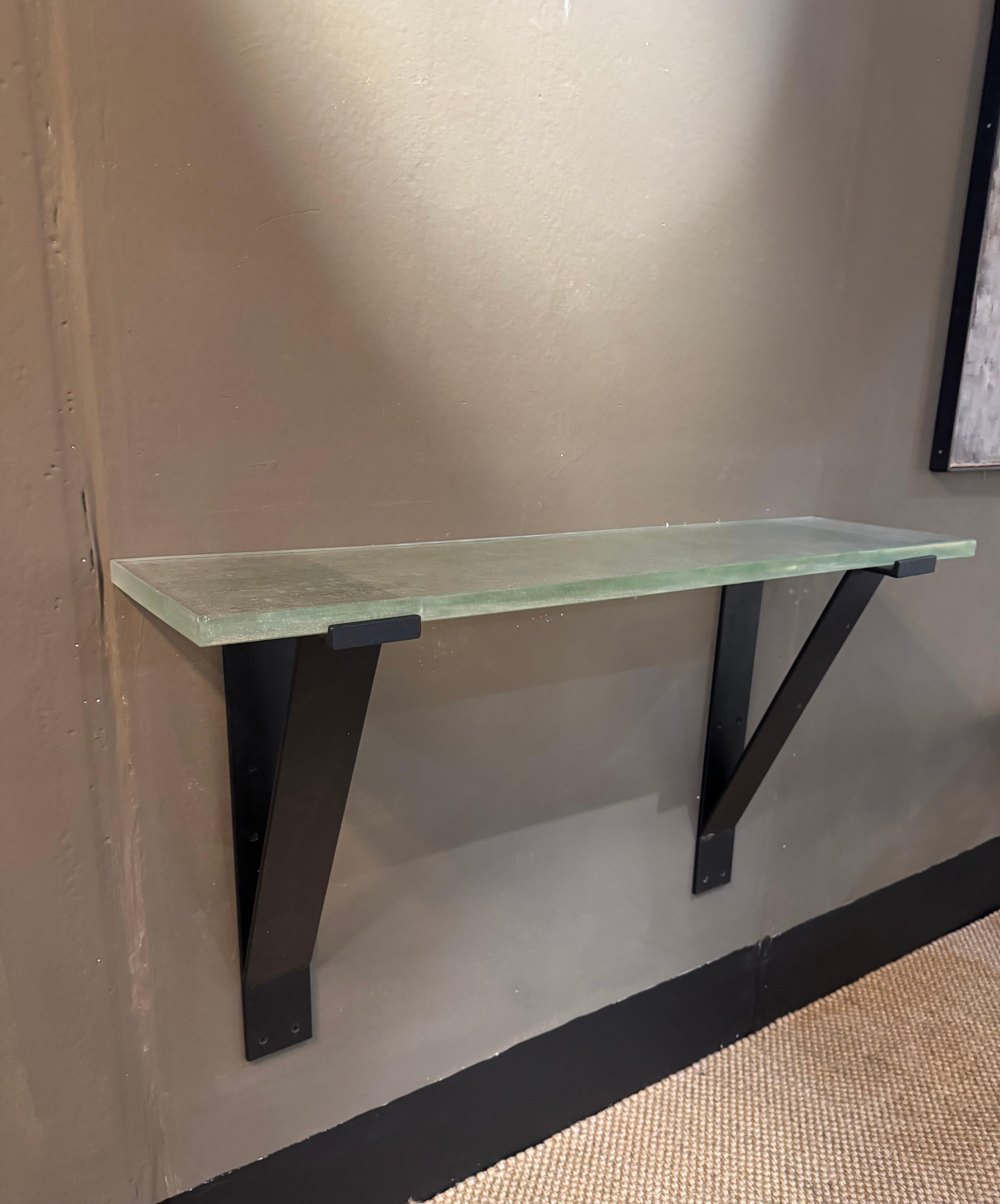 A very smart wall mounted iron and sand cast Saint Gobain glass console table. The glass is sand cast and dates from the 1930’s ( minor chip to one corner) the black iron painted brackets are later in period.
