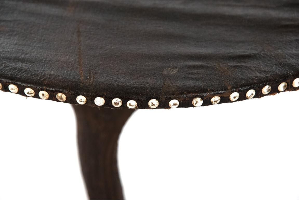 A small round table with leather and brass studded top and base made from fallow deer horns.

Measures: 30 x 23 x 23 in.