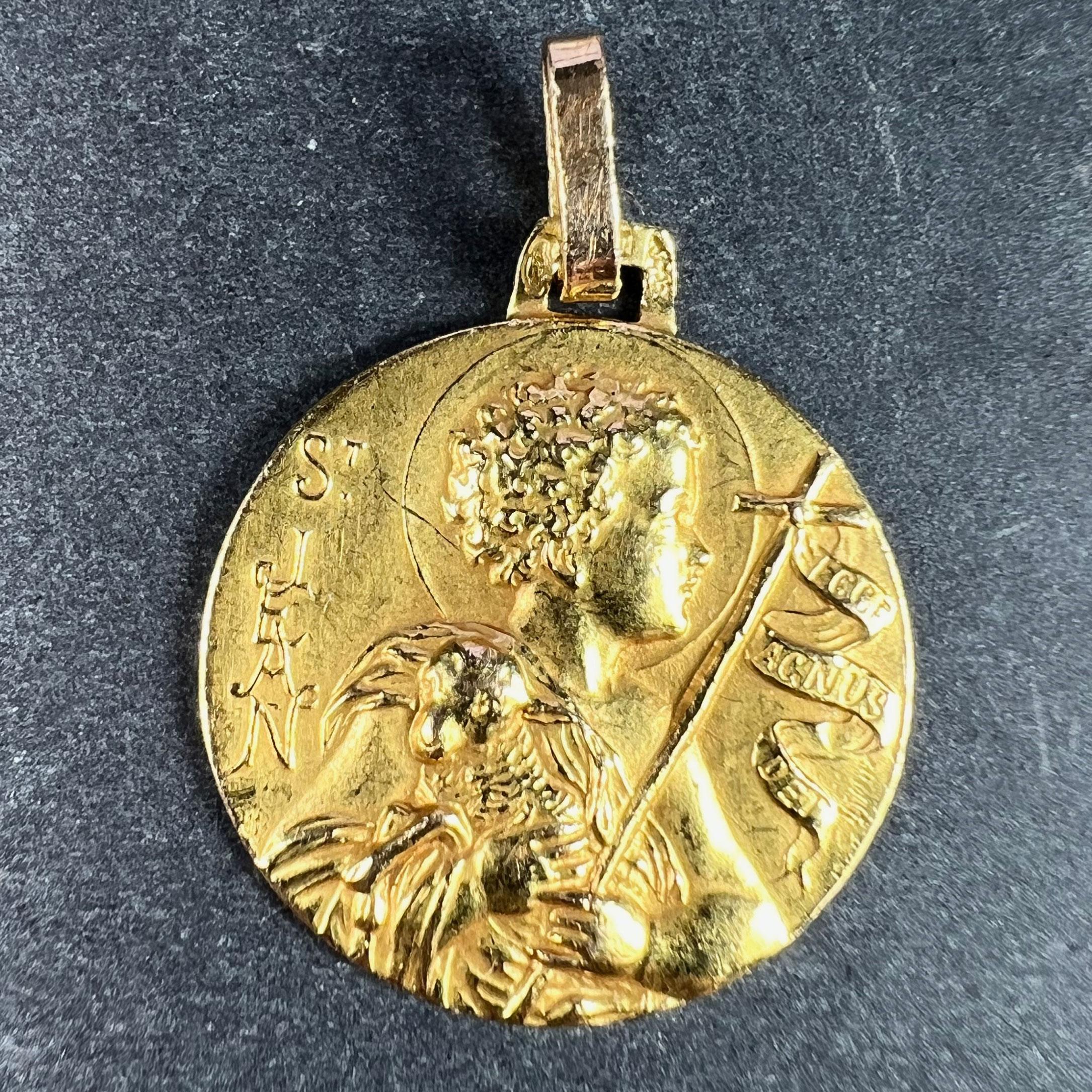 A French 18 karat (18K) yellow gold charm pendant designed as a medal representing Saint John the Baptist as a child with a cross and a sheep. The cross with a ribbon attached saying 'Ecce Agnus Dei' (Behold the Lamb of God). Signed by an unknown