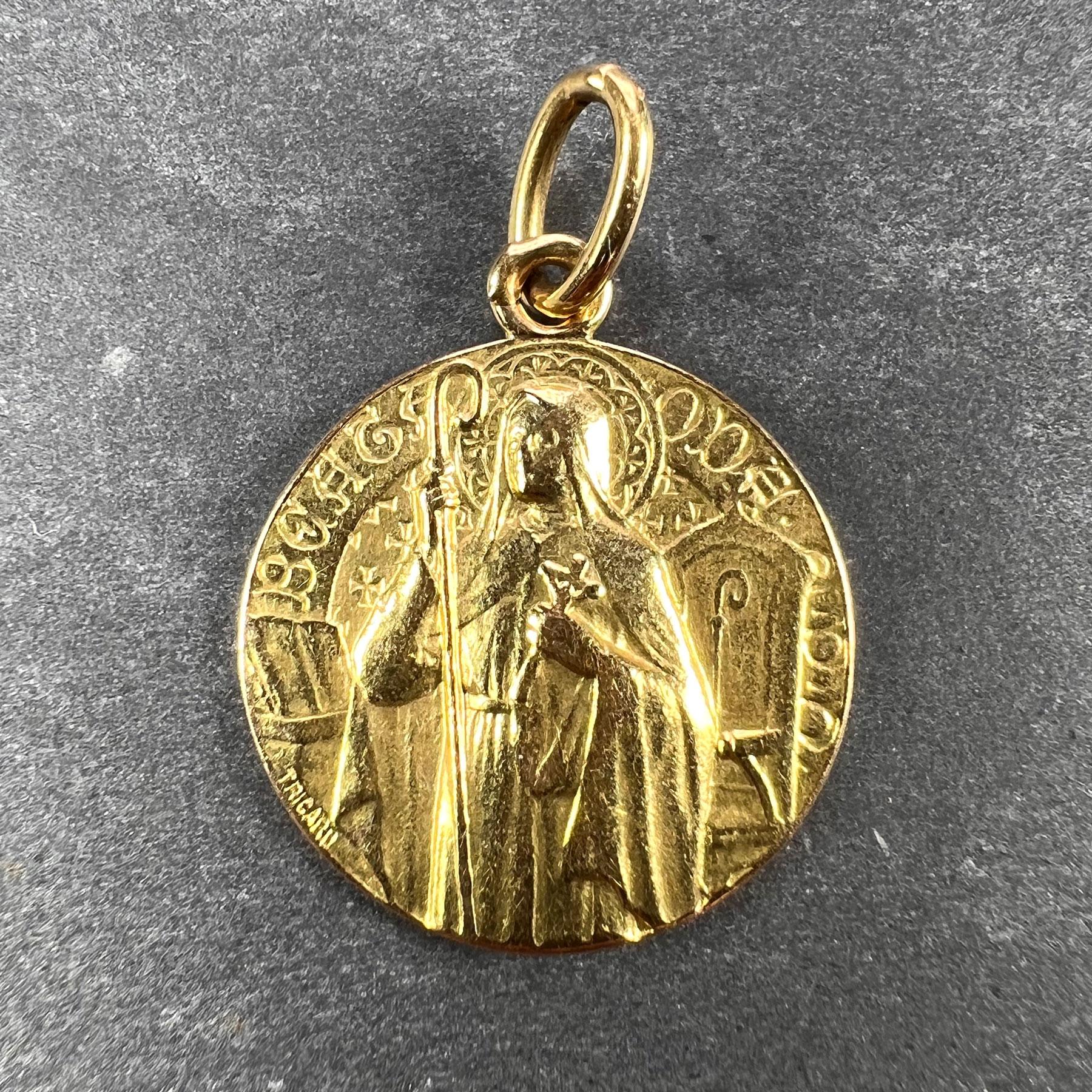 A French 18 karat (18K) yellow gold charm pendant designed as a medal depicting Saint Oda, inscribed ‘Beata Oda OPN’ (translation: ‘Blessed Oda pray for us’). Oda was born blind and was cured when she visited the relics of Saint Lambert. A wreath of