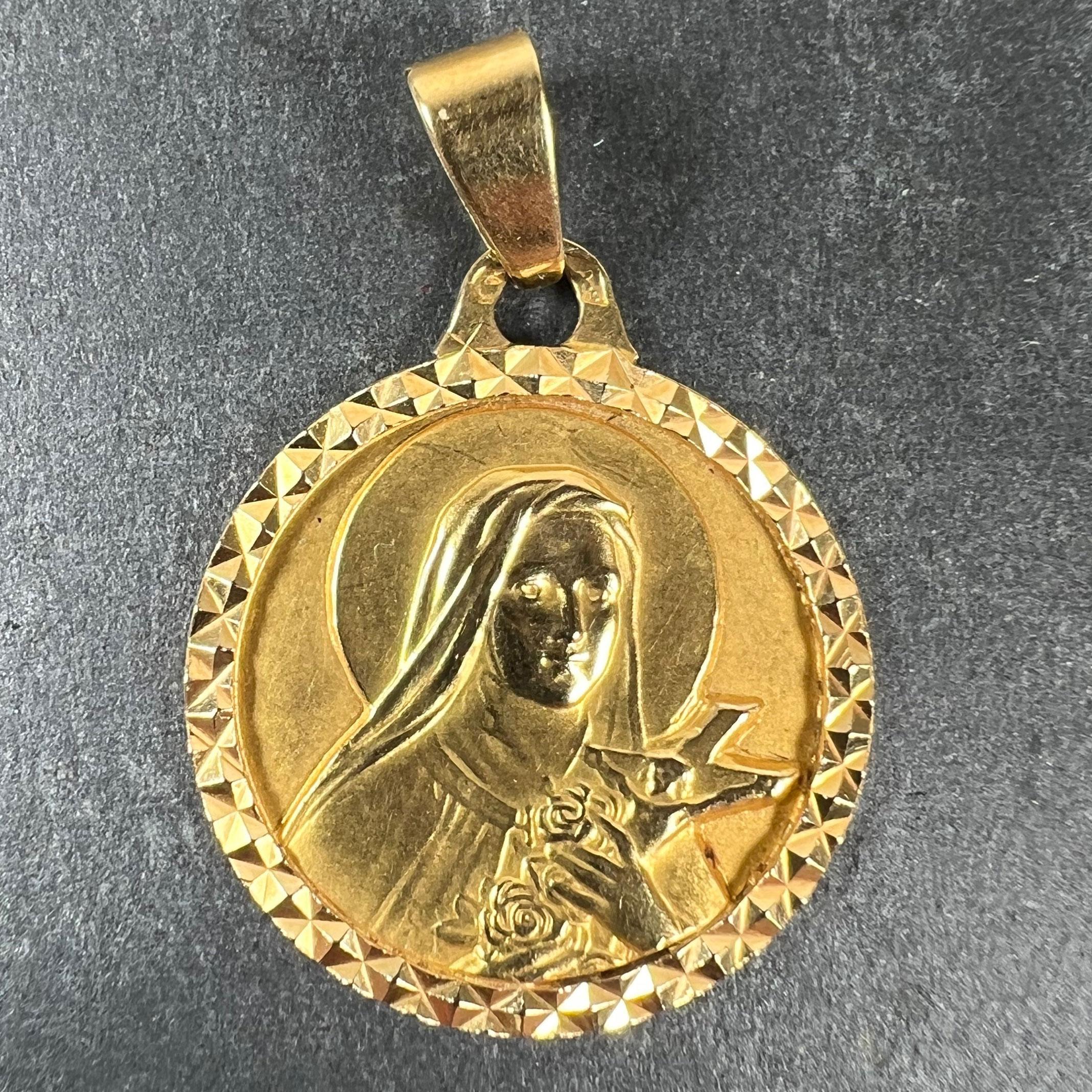 Ein französischer Anhänger aus 18-karätigem Gelbgold in Form einer Medaille, die die Heilige Therese mit einem Heiligenschein darstellt, die ein Kruzifix und einige Rosen hält. Der Rahmen ist facettiert, um das optische Interesse zu verstärken.