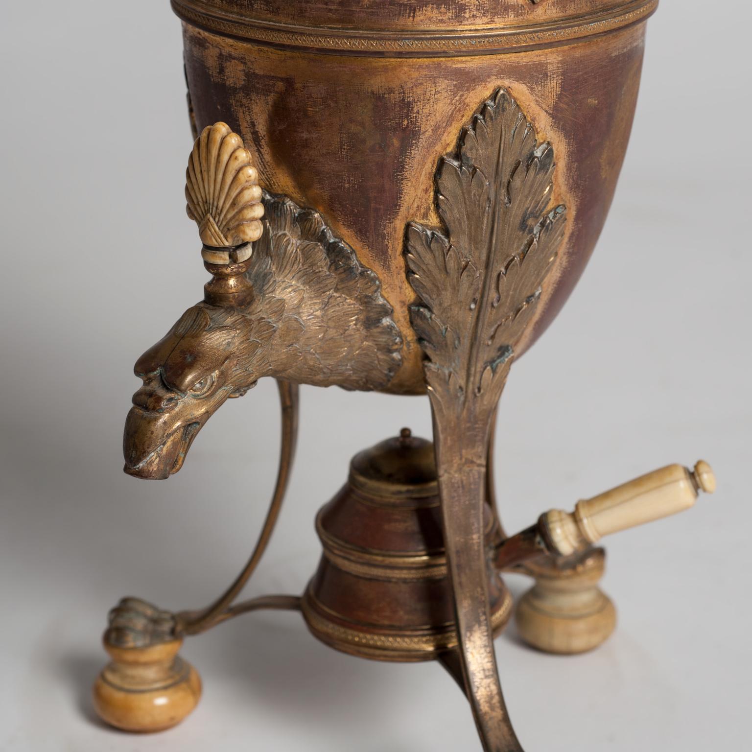Samovar or coffee urn in copper and bronze signed by George Falkenberg, with Empire-style design, composed of a central body supported on three legs that end in the form of an eagle's claw and a bone base. The samovar's fountain has the shape of an