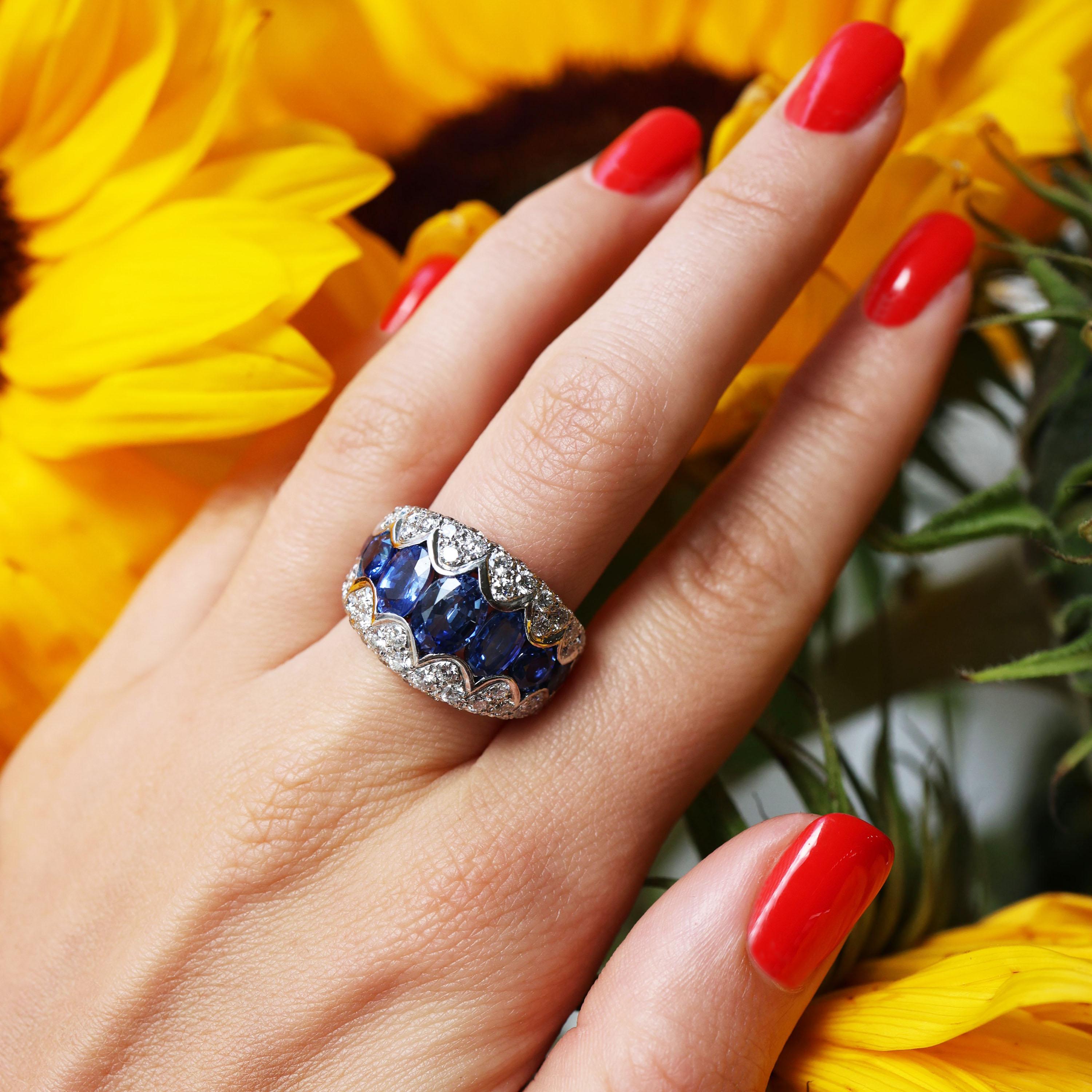 A sapphire and diamond ring, set with a central row of graduating oval and round faceted Ceylon sapphires, with a scalloped edged surround, pavé set with round brilliant-cut diamonds, mounted in 18ct white gold, with a French eagle head mark for