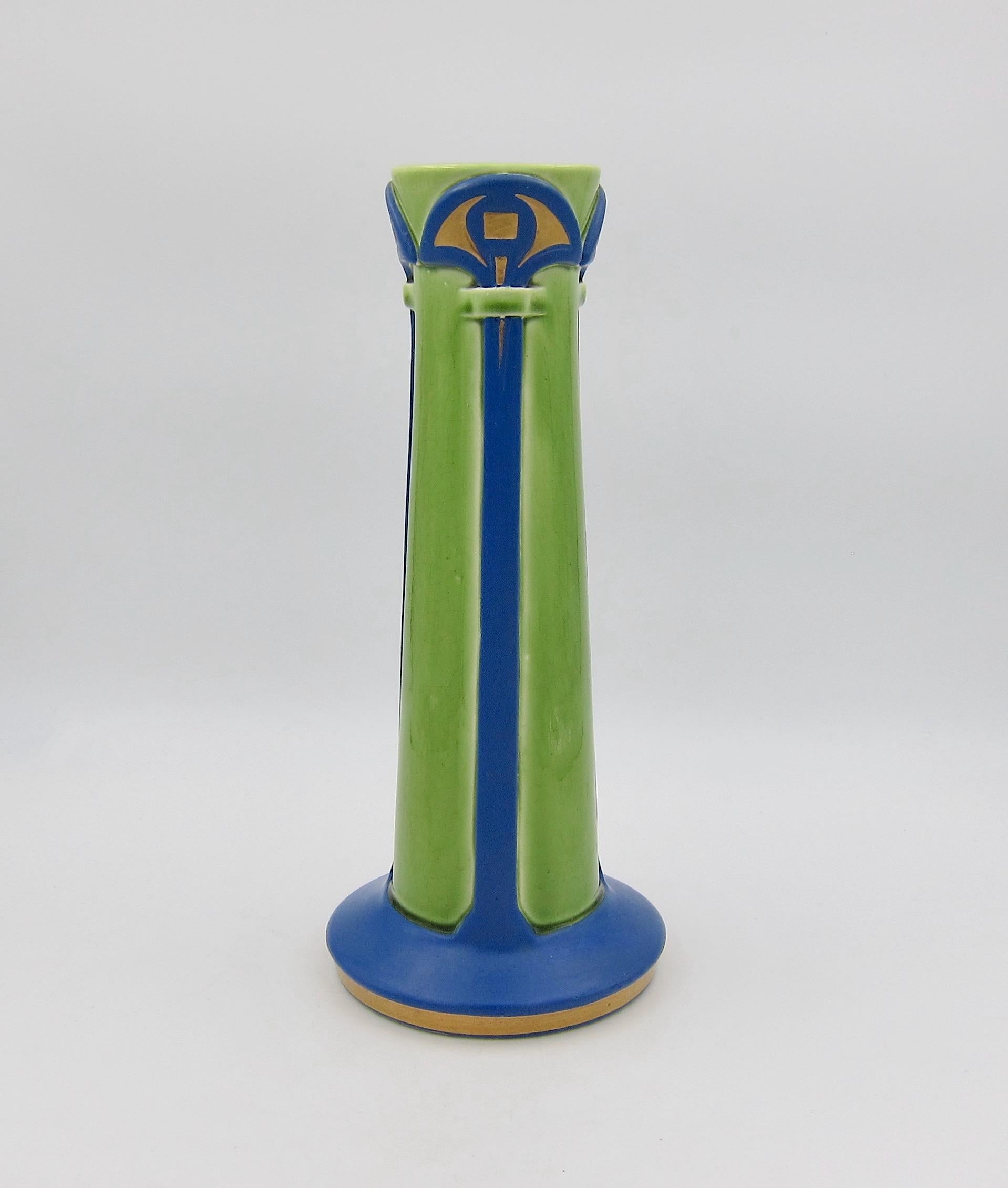 An early 20th century French art pottery vase date marked for 1906. The antique vase from the Sarreguemines factory is shaped like an architectural column or pillar on a round pedestal base and decorated in a bright, bold majolica glaze of glossy