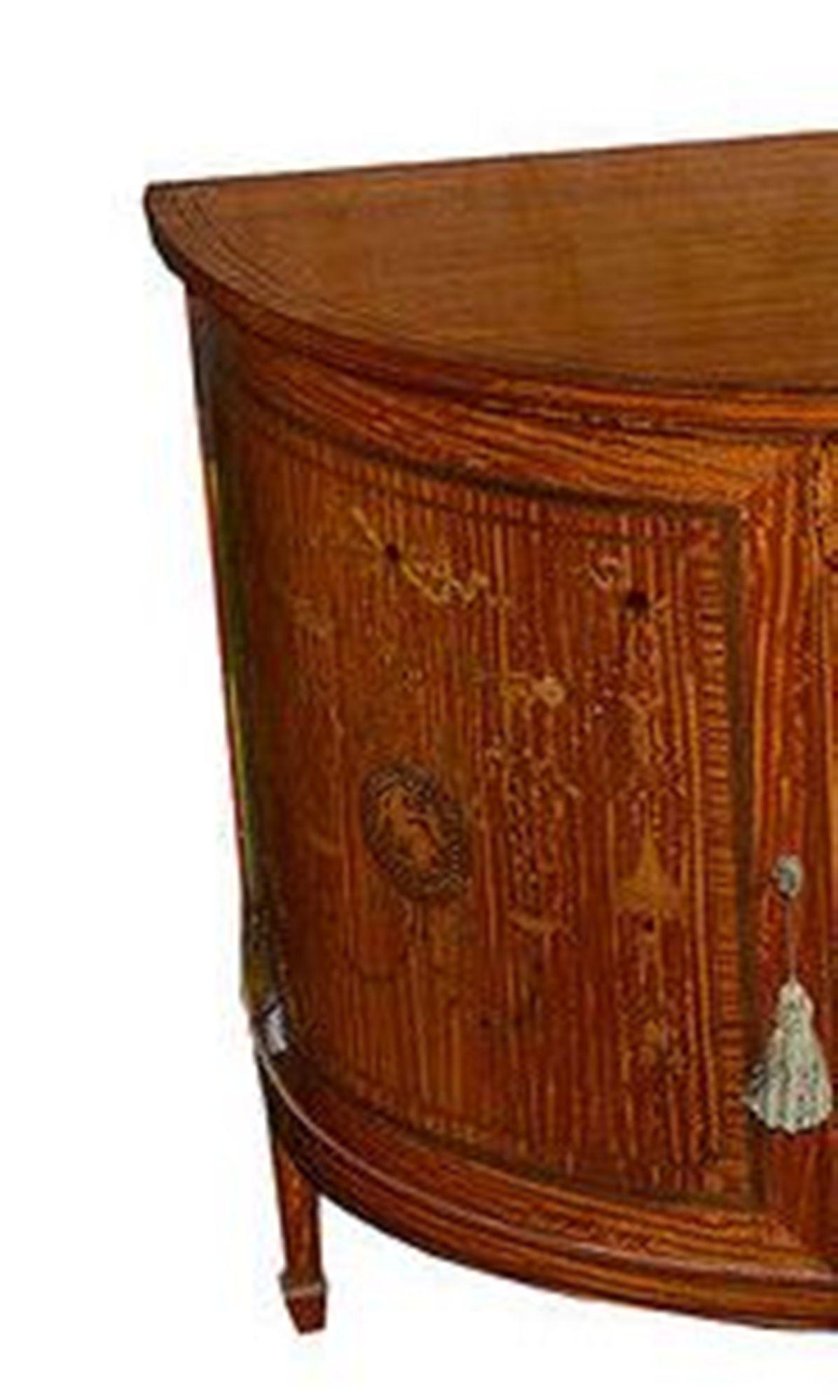A French satinwood and marquetry inlaid D shaped sideboard of exceptionally fine quality.

The side and door panels and mahogany lined fronts, all with classical influenced inlays incorporating seated Grecian figures and urns and trailing