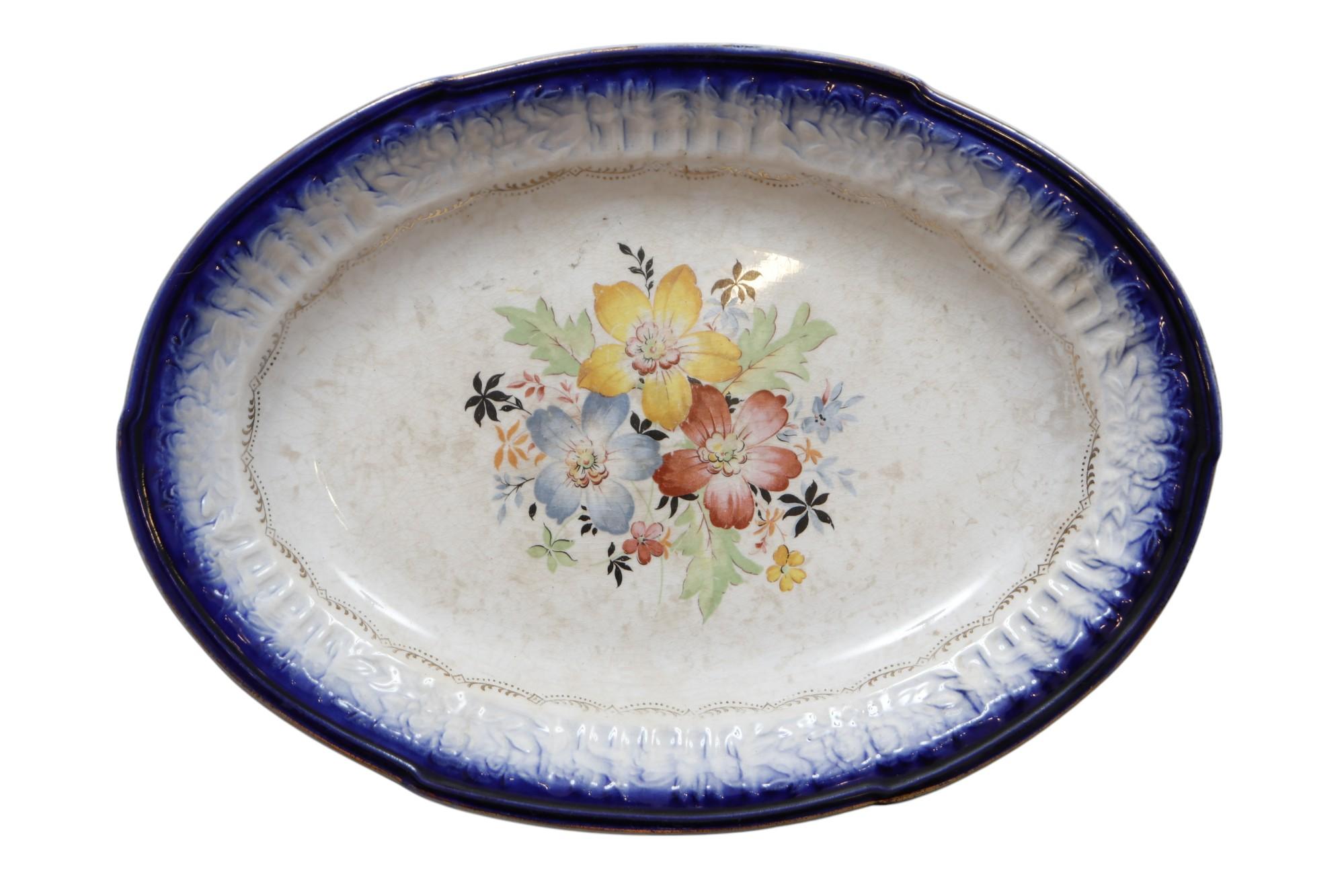 Un piccolo piatto di ceramica francese Saxon China Co. della metà del secolo scorso. Decorato con un labbro in rilievo floreale blu cobalto, uno spruzzo floreale centrale e delicati fiocchi in oro 22 carati. Marchio del fabbricante sotto.