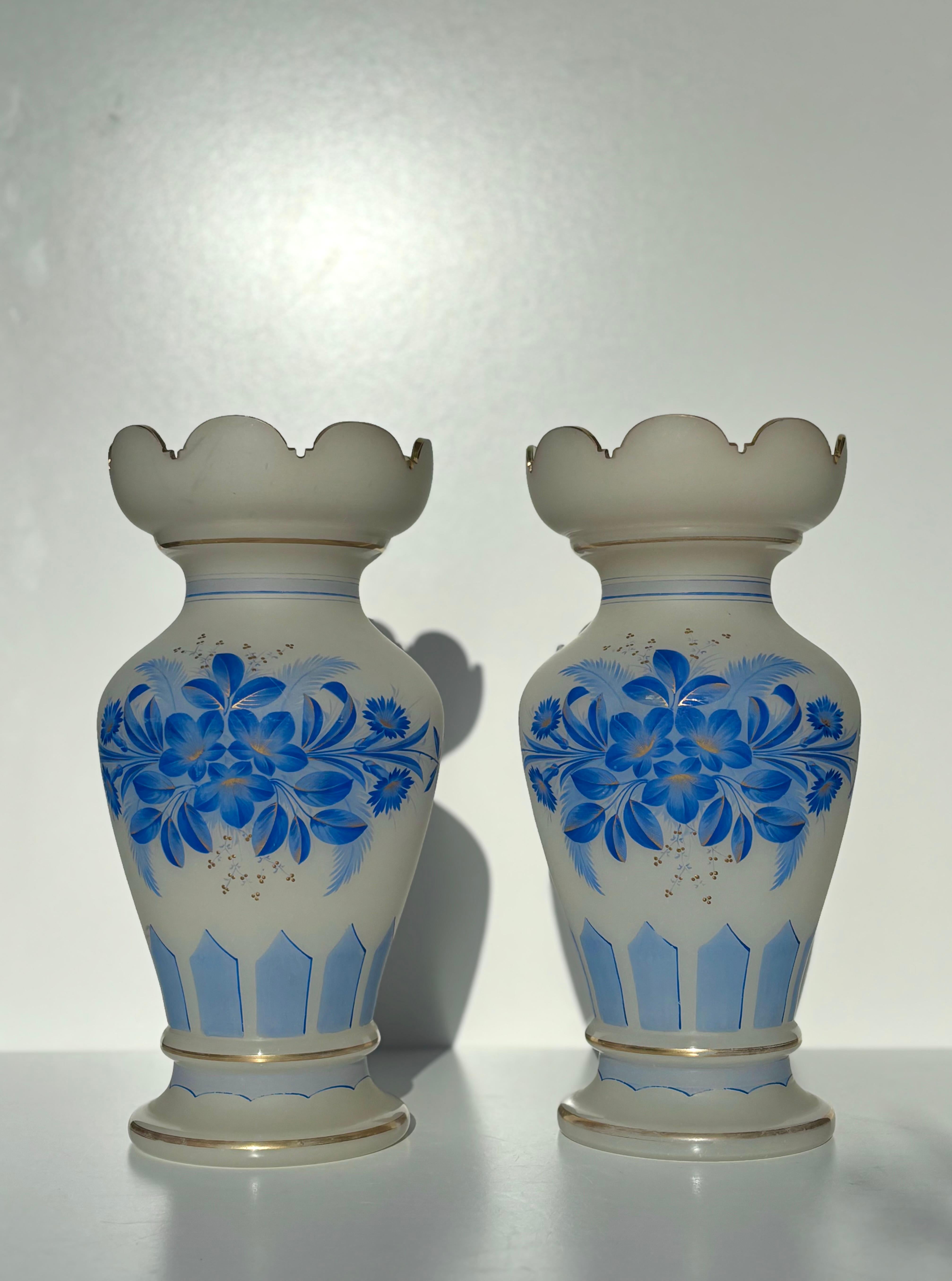 Vases en verre blanc des années 1940 avec de beaux bords festonnés et des décorations florales et lignées peintes à la main dans des nuances de bleu vif avec des accents jaunes et dorés.
Belle condition vintage. 
Le prix correspond à la paire.