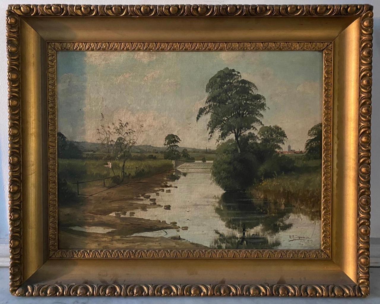Charmante huile sur toile représentant un paysage de campagne traversé par un ruisseau, au bord duquel un arbre a poussé et s'y reflète. À l'arrière-plan, à droite de la toile, on aperçoit un village d'où dépasse un clocher d'église. 
Signé
