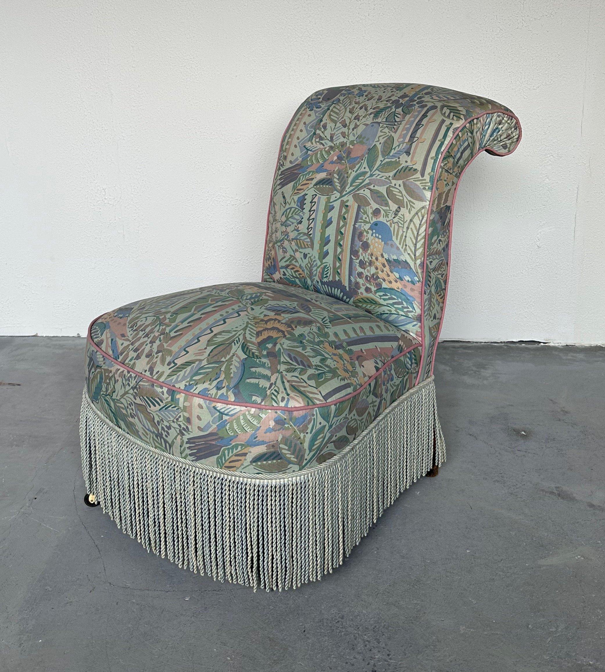 This lovely 19th century French Napoleon III slipper chair features a gracefully scrolled back, and has been upholstered in an elegant fabric with an abstract leafy design with birds. It is expertly finished in rose colored piping and complimentary
