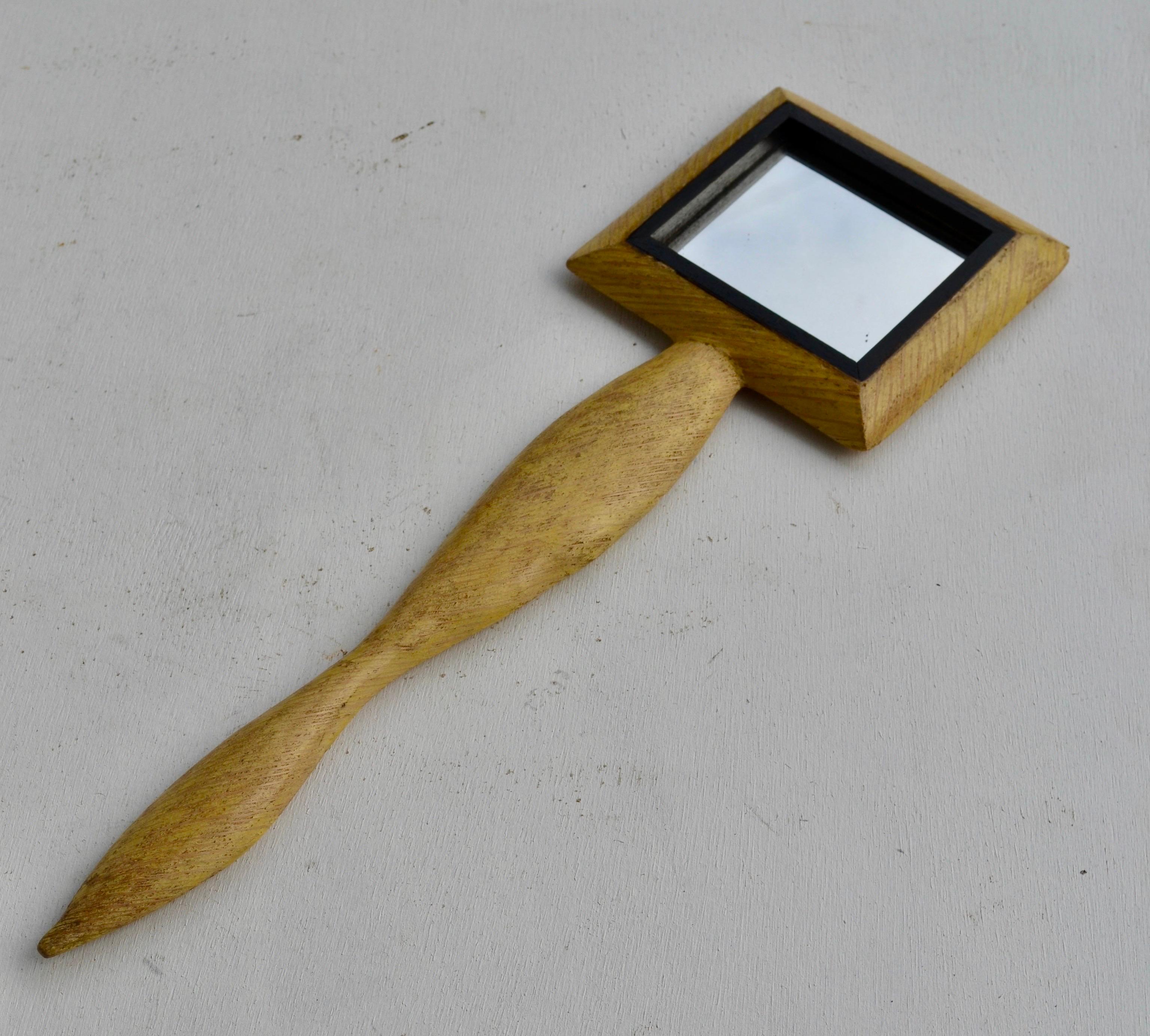 Elegant French hand mirror from the 1950s, beautifully crafted in carved wood and evoking the spirit of Augusti’s refined artisanal vocabulary. The handle features an organic, elongated silhouette with subtle sculptural curves, giving the piece a