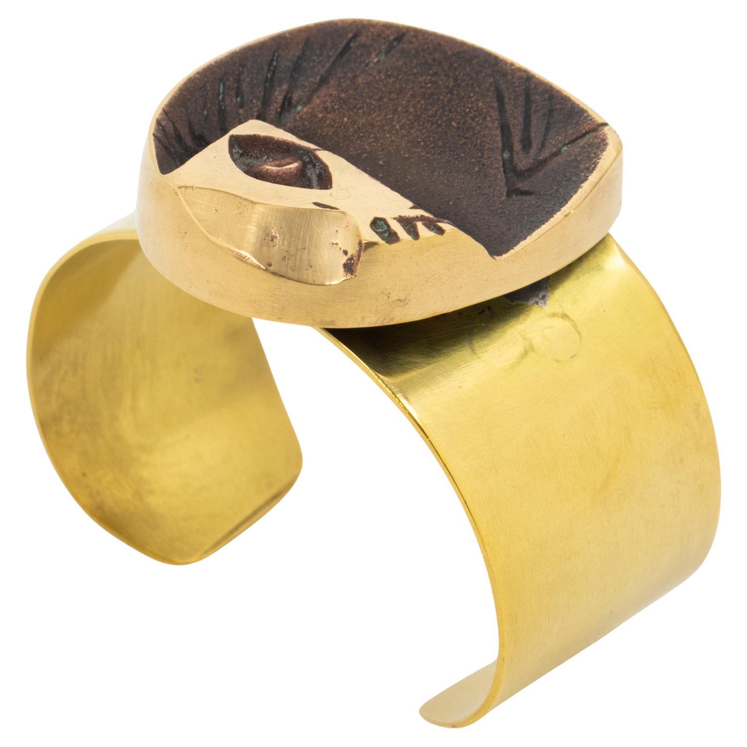 French sculptor and painter Henri Nogaret (1927 -) created this sculptural brutalist bronze and brass cuff bracelet in the 1960s. The large brass band is topped with a gilded bronze modernist abstract sculpture ornament. The engraved signature is on