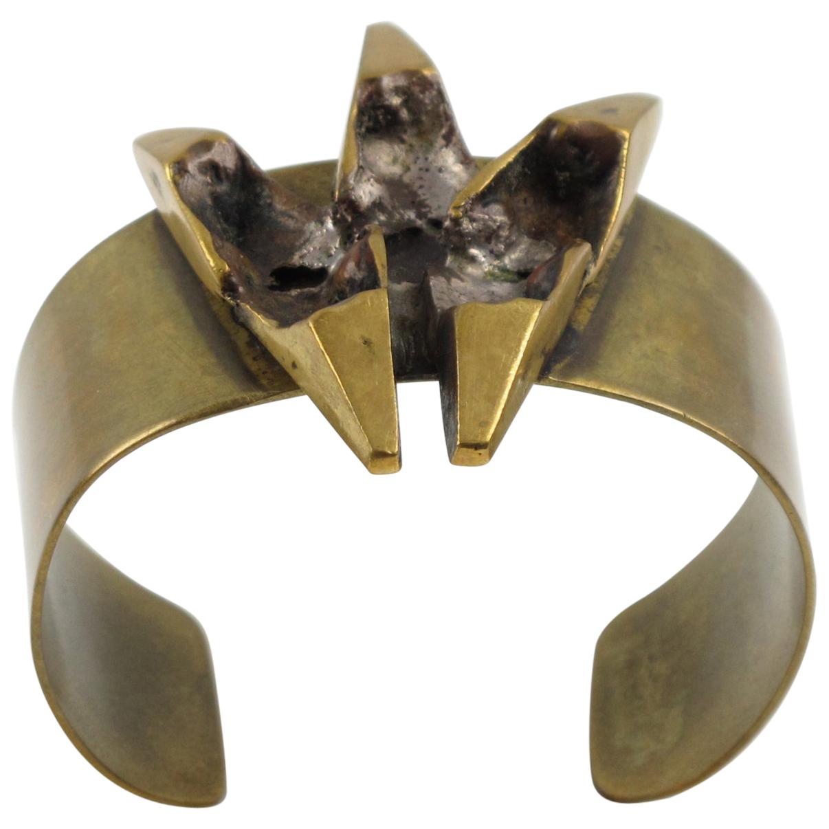 This impressive sculptural brutalist bronze cuff bracelet was designed by French sculptor and painter Henri Nogaret (1927 -). The large brass band is topped with a Mid-Century modernist abstract ornamental sculpture made of gilded bronze. The