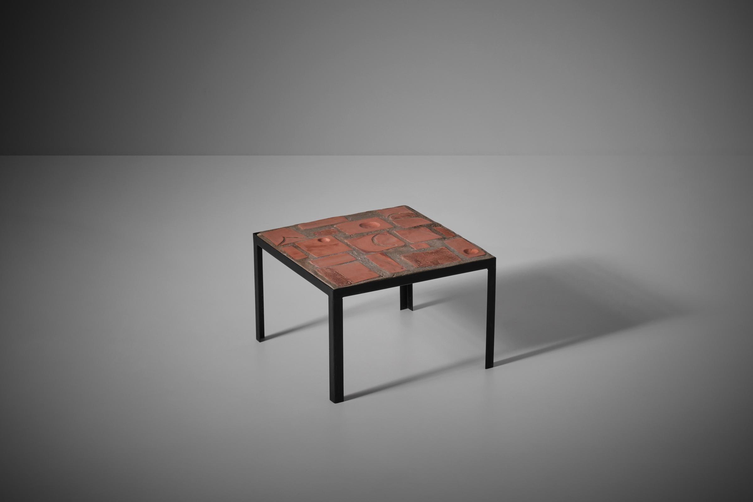 Sculptural side table by an unknown artist, France 1960s. The table displays an interesting composition of small reliefs handmade from terracotta. The terracotta tiles lie in a bed of concrete, the square top lays in a modest metal base. Very