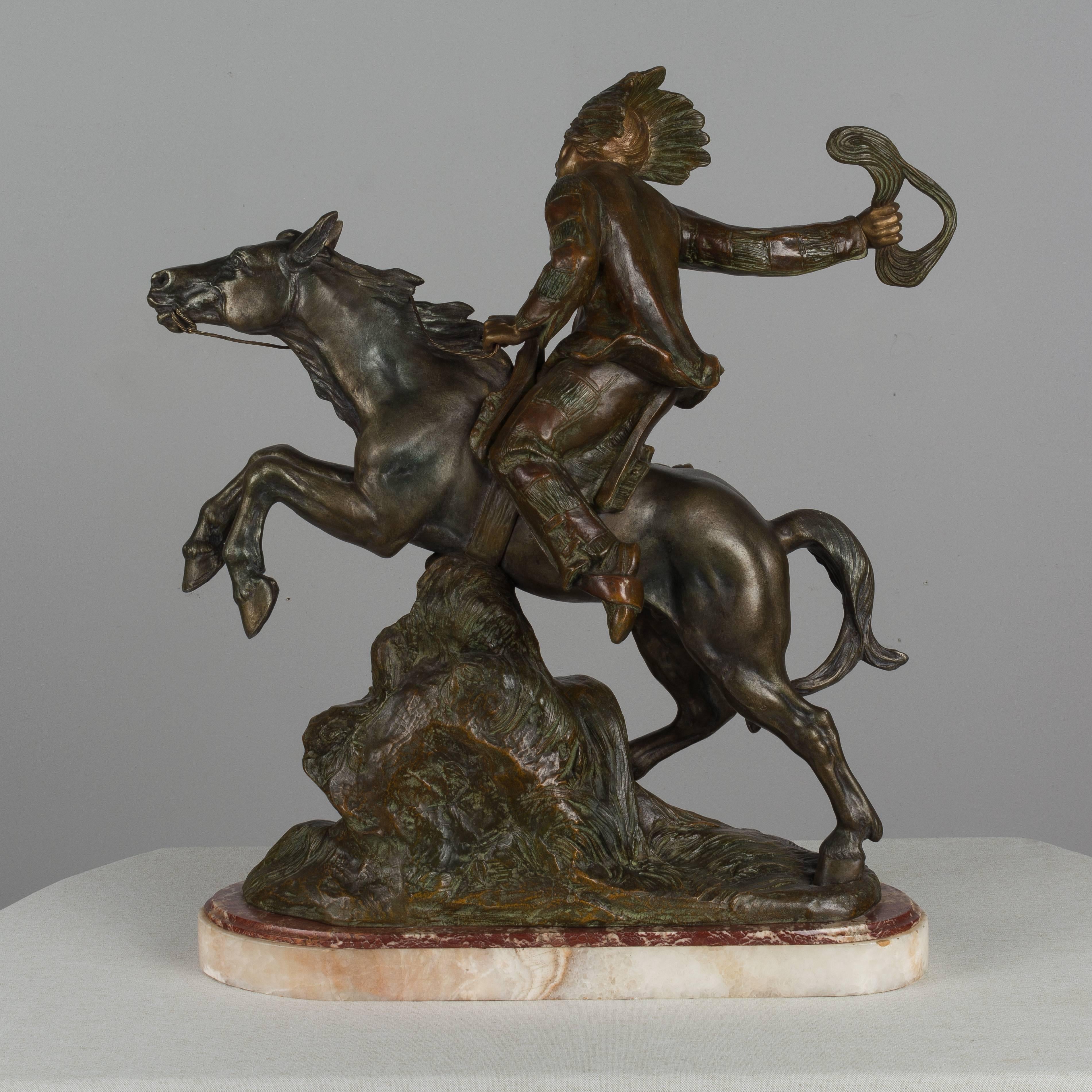 A large metal sculpture of a Native American man riding a galloping horse. Entitled 