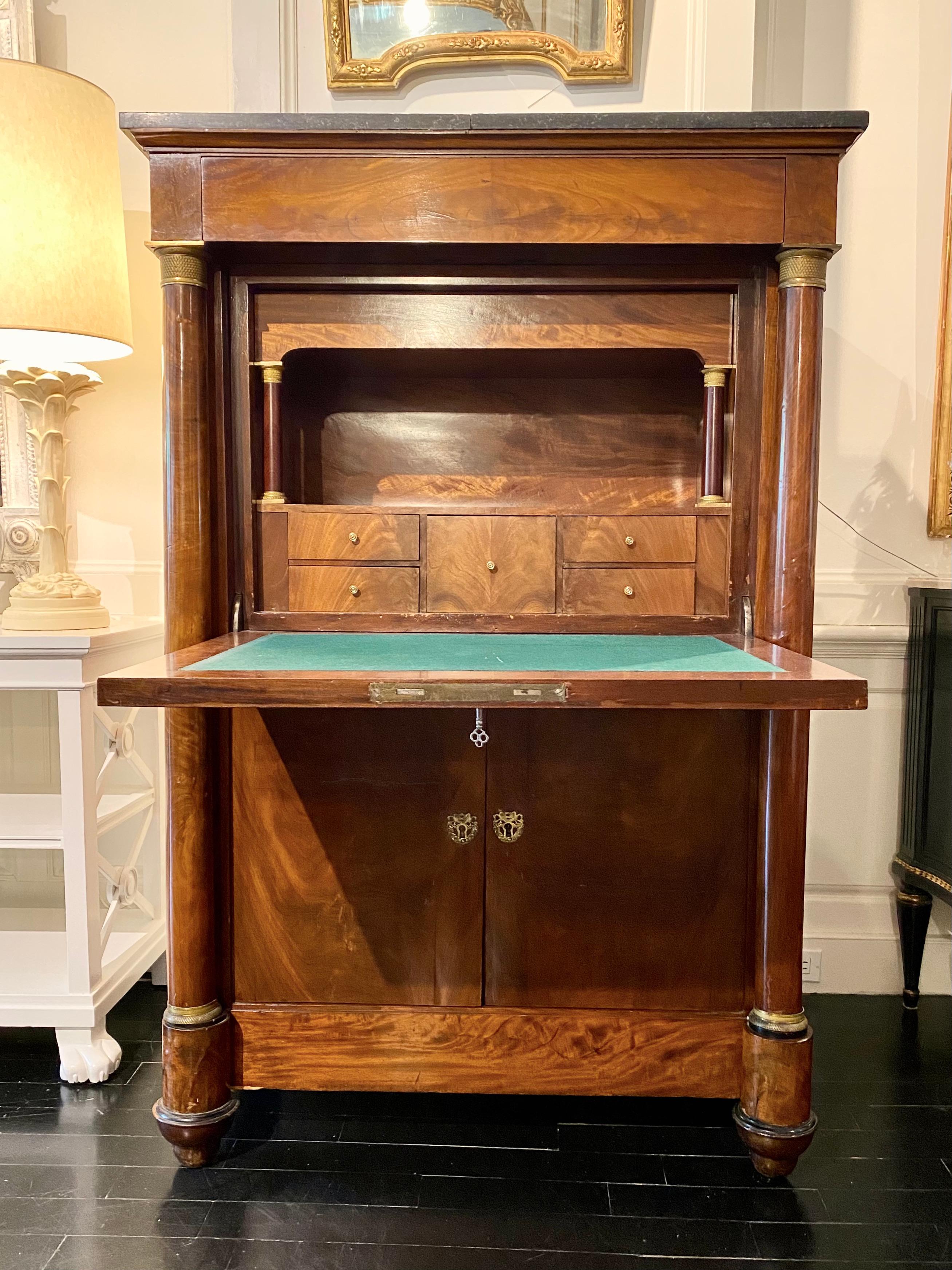 French first Empire period Secretaire à Abattant, also known as a drop-front secretary, fall front or cantilevered desk. Under the dark grey marble top is a secret, entablature drawer. A cantilevered fall front opens to reveal several drawers, a