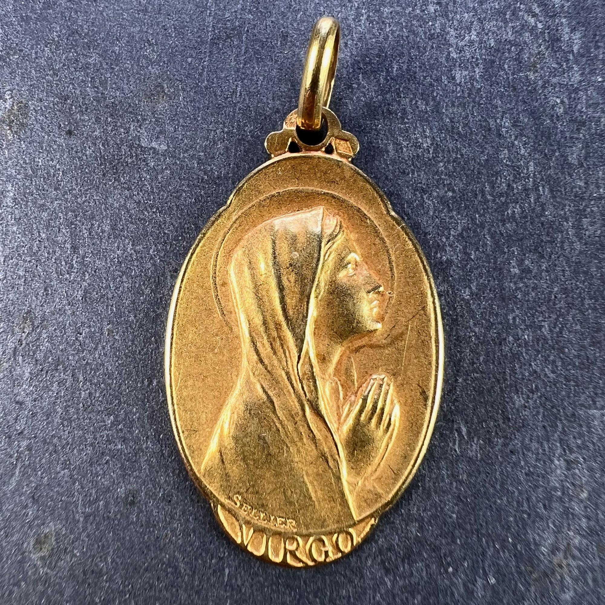 An 18 karat (18K) yellow gold charm pendant designed as a medal depicting the Virgin Mary praying in profile over the word ‘VIRGO’. Engraved with a monogram for FB or BF and the date 26 Mai 1940. Signed Sellier, stamped with the eagle mark for 18