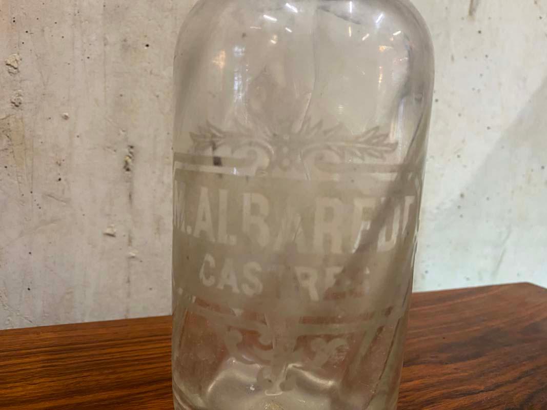 Antike kleine Siphonflasche aus Frankreich aus den Jahren um 1900. Die Seltzerflasche hat einen Verschluss aus Zinn, in den der Name M. ALBARÈDE und die französische Gemeinde MAZAMET eingeprägt sind, und einen Körper aus Klarglas, in den der