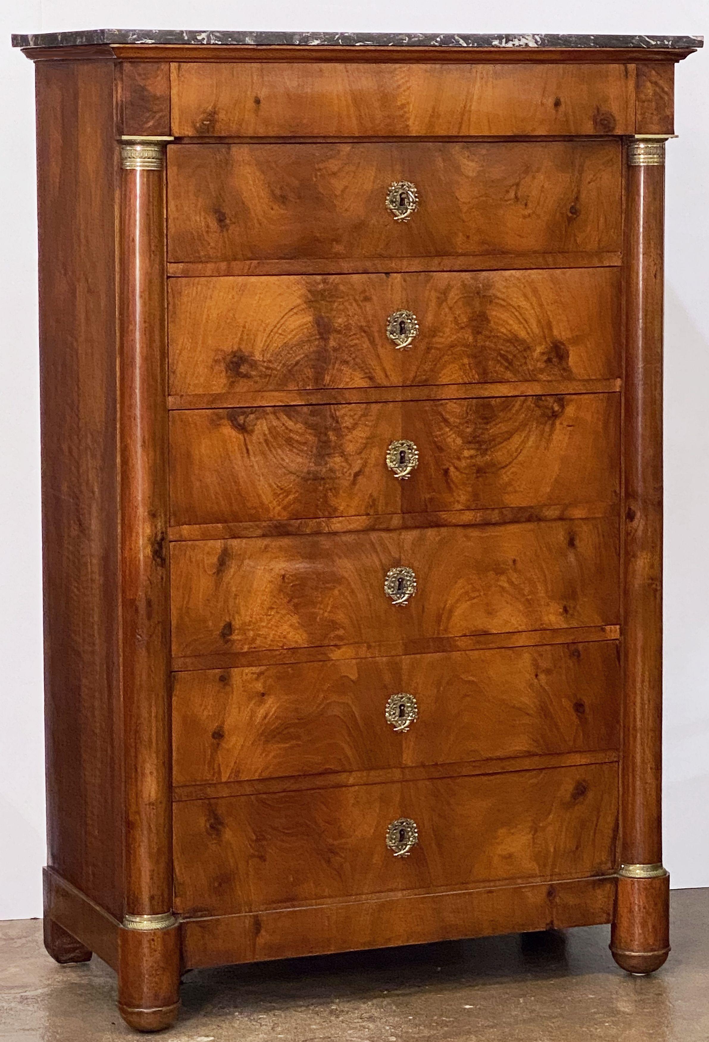 A handsome French semainier or tall chest of walnut with marble top, featuring a slightly narrower top drawer over six larger drawers beneath. 
The drawer fronts with beautiful carefully matched walnut veneers. 
The six larger drawers have