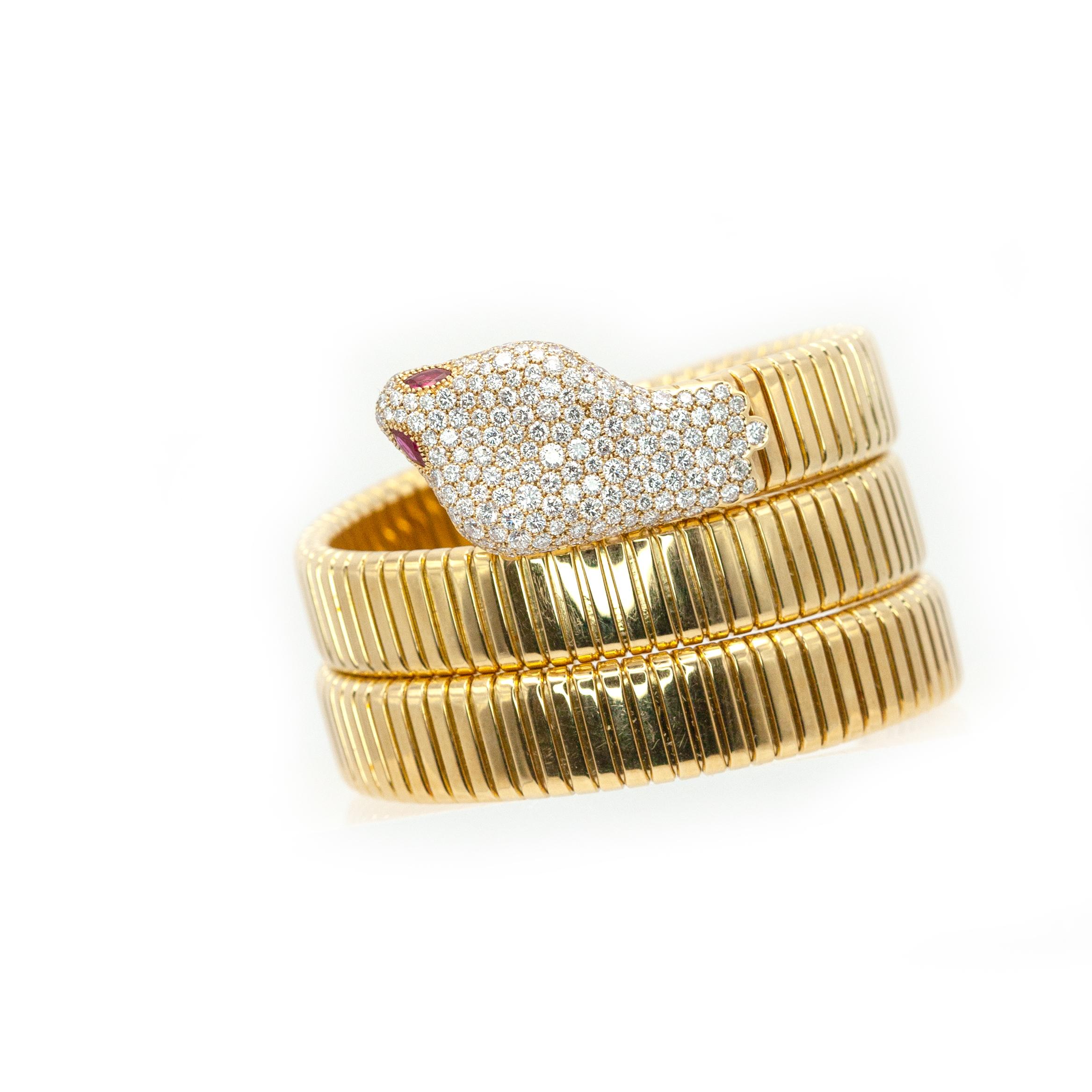 Un suggestivo bracciale a serpente realizzato in oro giallo 18 carati con struttura tubogas flessibile, che si avvolge elegantemente intorno al polso in un doppio giro. La testa del serpente è incastonata con pavé di diamanti taglio brillante di