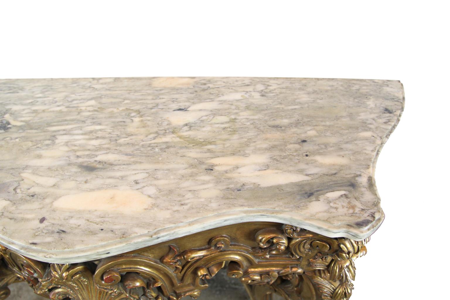 French Serpentine marble-top console table, figured marble top, gilded base with central stylized reticulated shell motif, cabriole legs adorned with bell flower and acanthus leaves connected with arched stretcher.