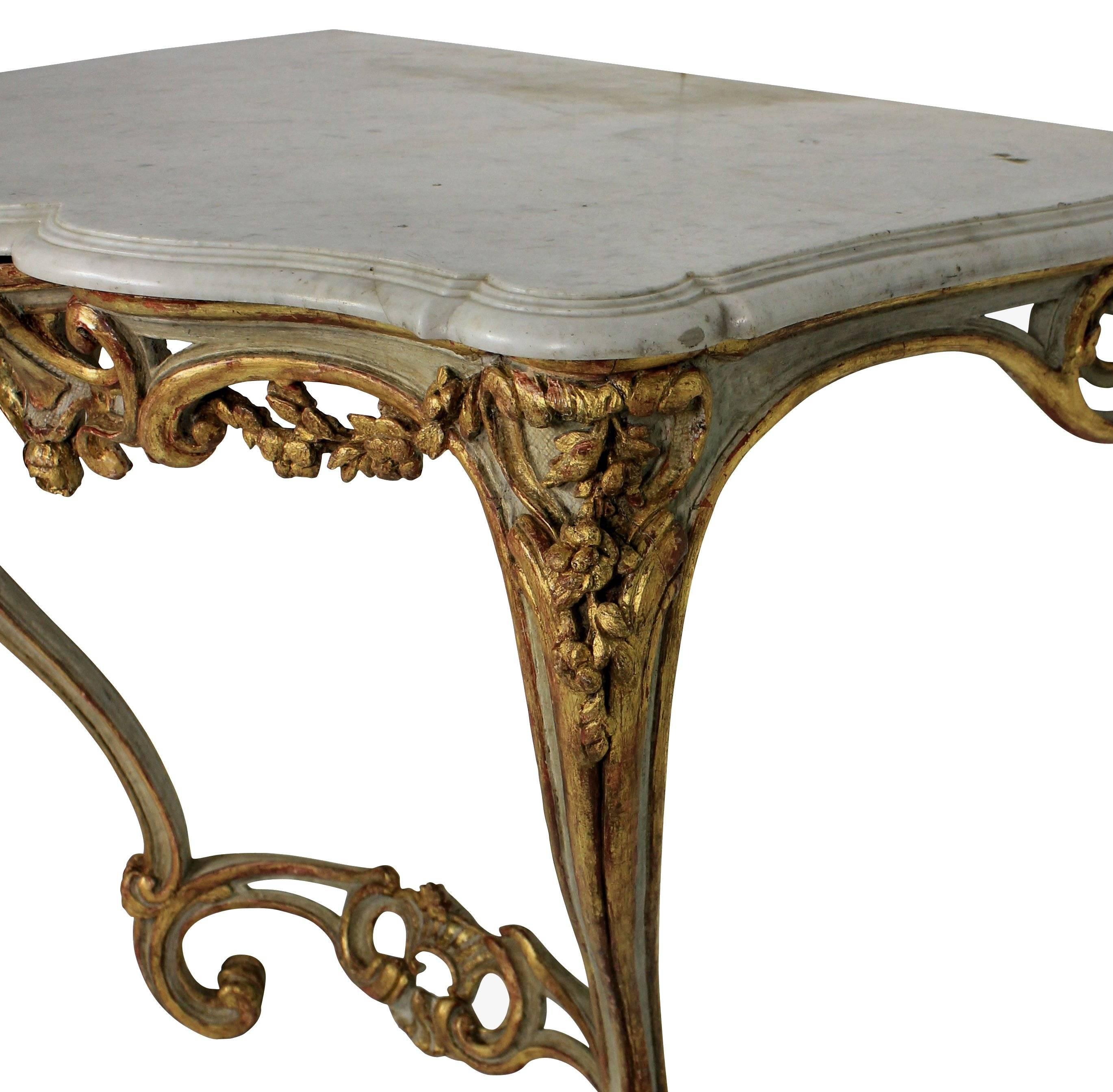 A French carved, painted and gilded serpentine console with a dove grey shaped marble top.