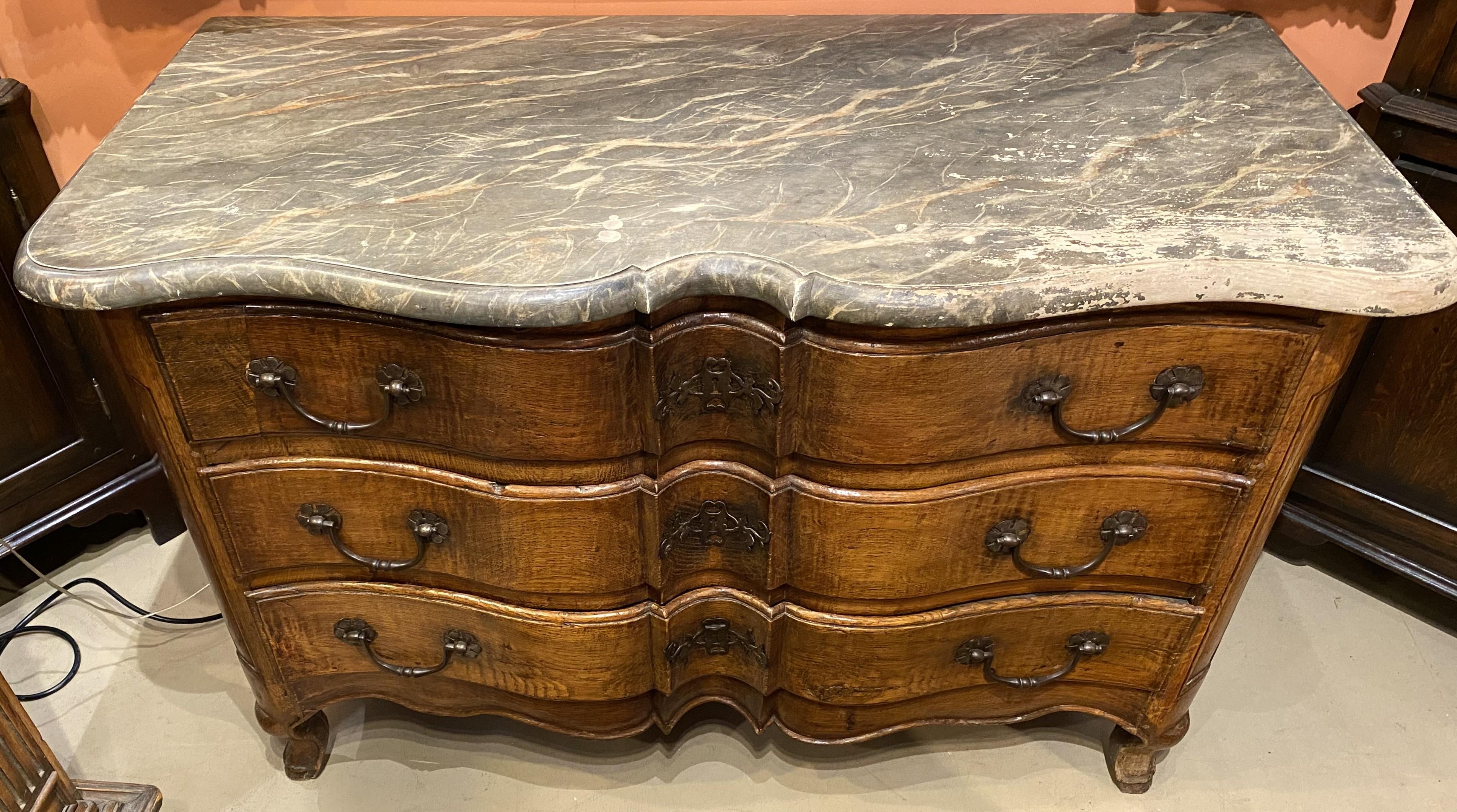 A nice example of a French walnut three drawer commode in serpentine form, with conforming faux marble painted top and decorative hardware, carved paneled corners, a nicely shaped carved skirt, supported on splayed French feet. Dates to circa 1760,