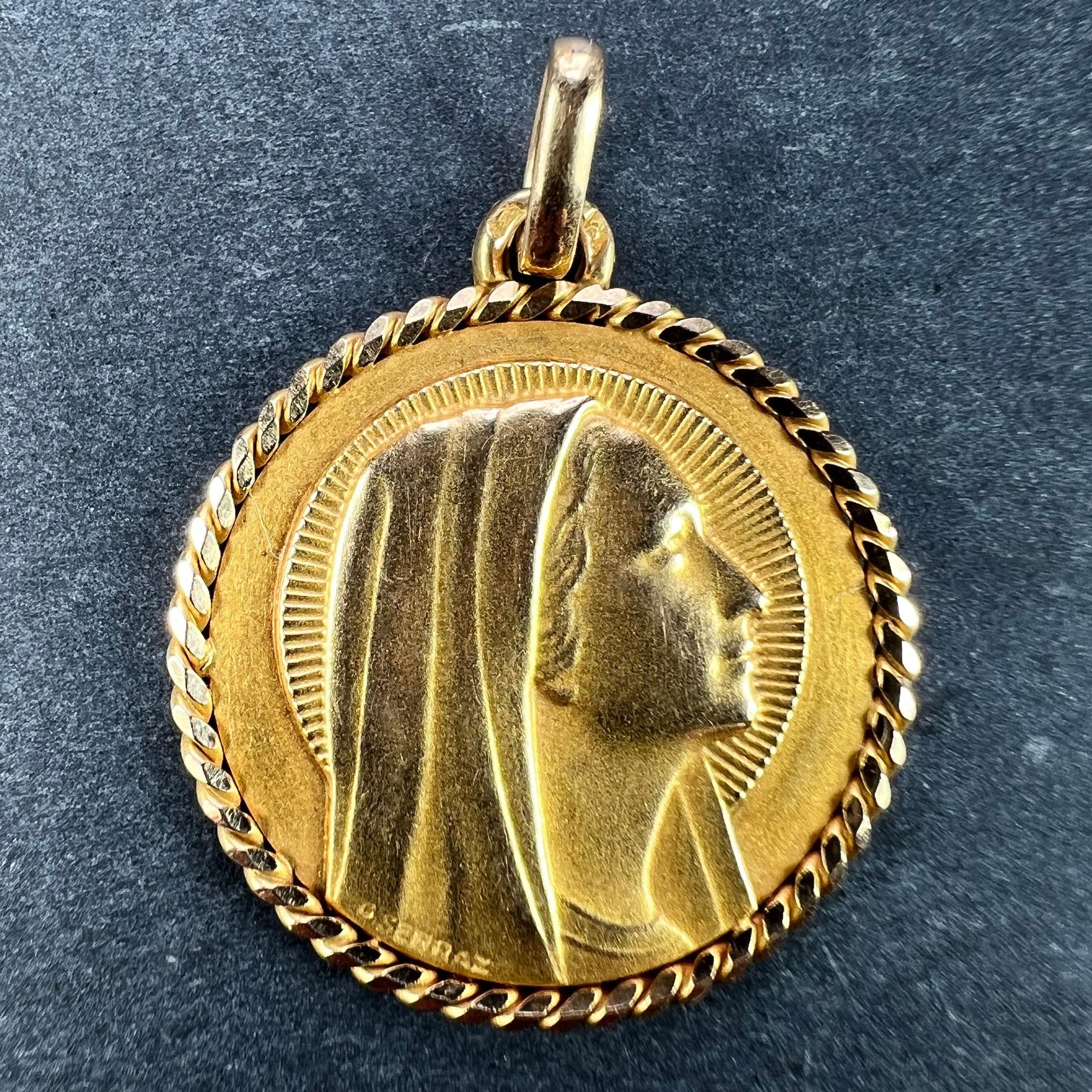 An 18 karat (18K) yellow gold pendant designed as a round medal depicting the Virgin Mary with a halo and a twisted rope surround. Signed G. Serraz. Stamped with the eagle’s head for French manufacture and 18 karat gold with an unknown maker's