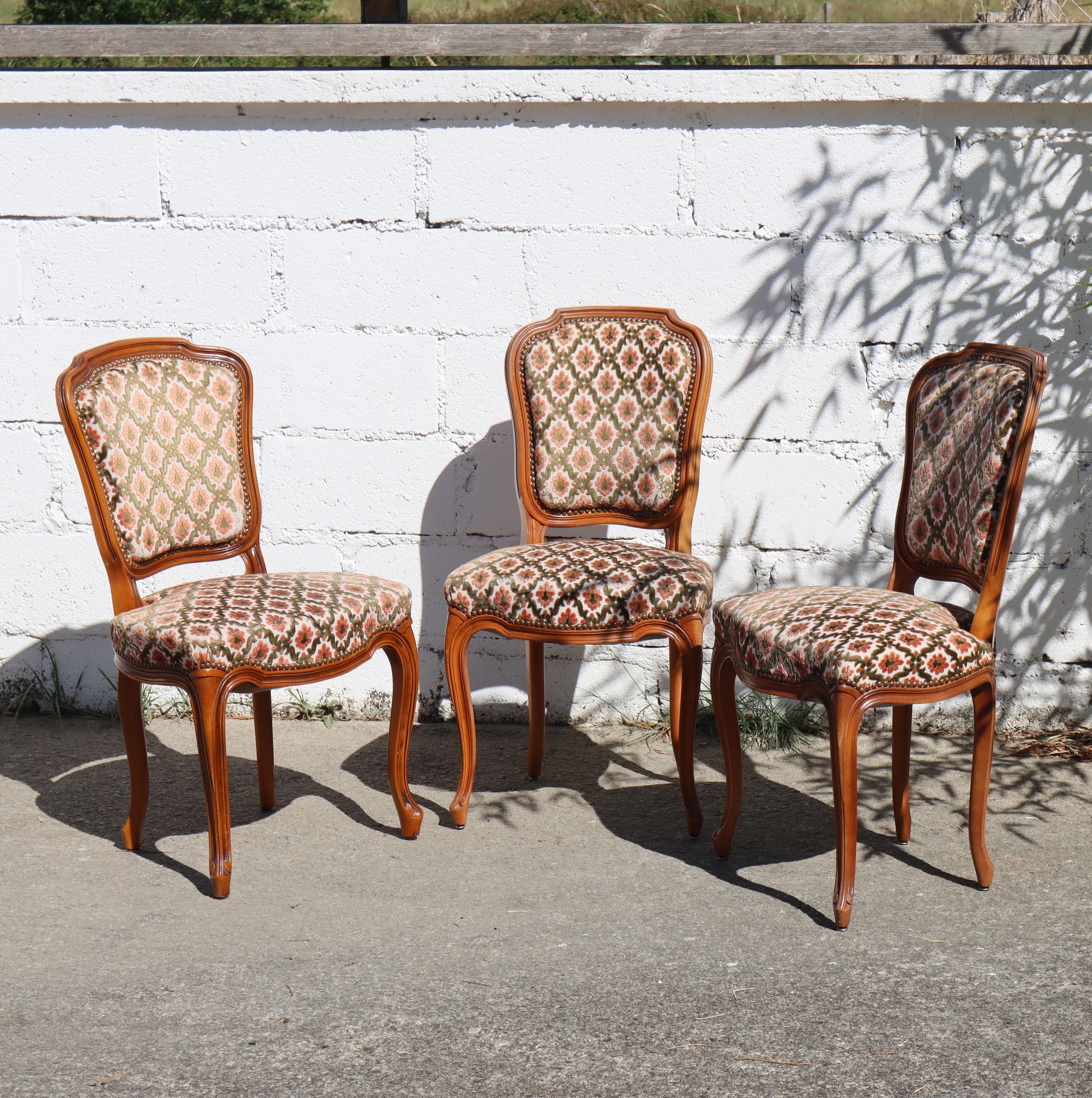 Set of 3 comfortable upholstered Dining Chairs Style Louis XV from the 70s.
Hand-carved made of solid cherry wood ,they feature beveled contours and floral details on the tabletop, legs, and front of the seat.
Solidly constructed Chairs -