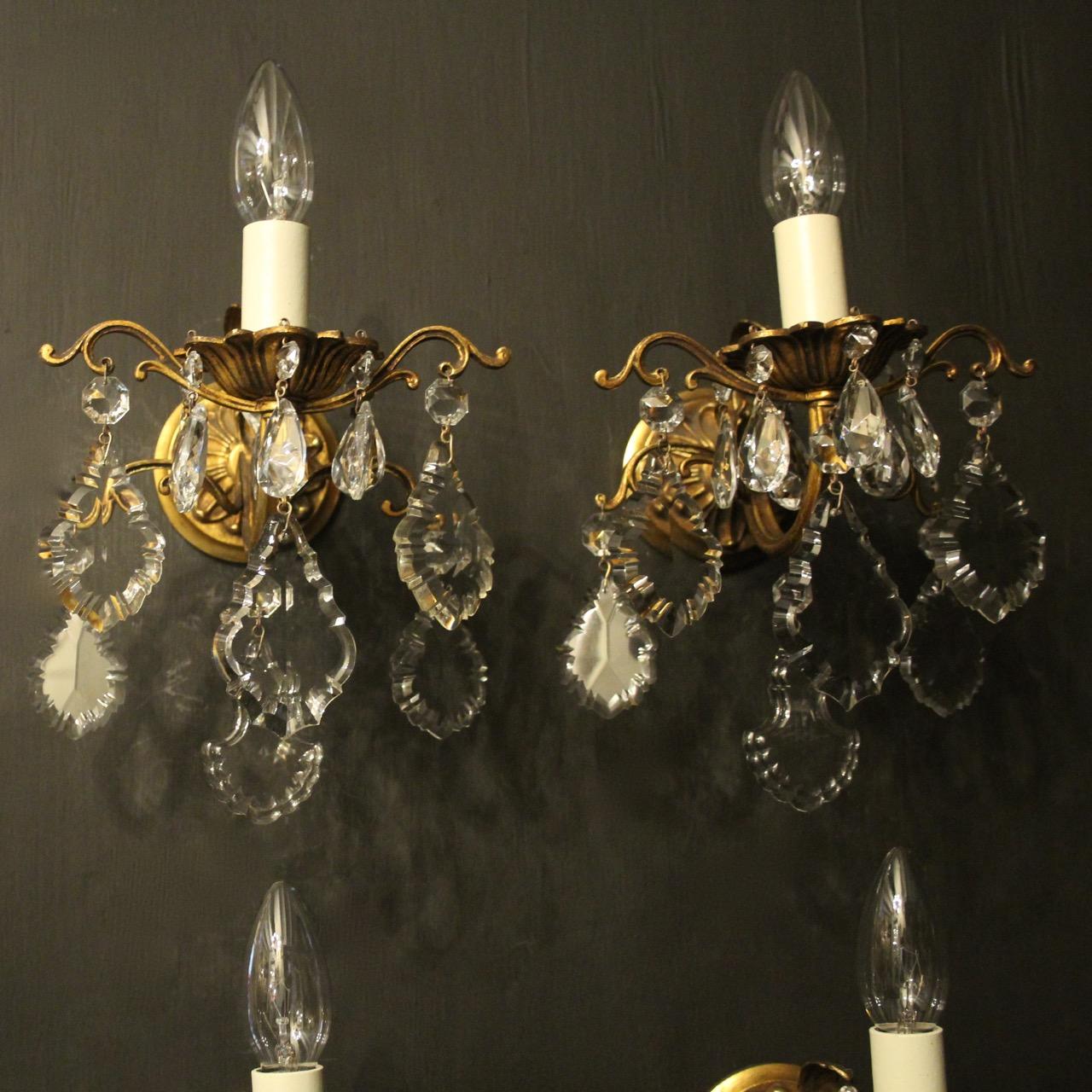 A French set of 4 gilded brass and crystal single arm antique wall lights, the scrolling arms with leaf bobeche drip pans, issuing from a folited circular leaf backplate and decorated overall with French Slab crystal faceted pendants, nice scale