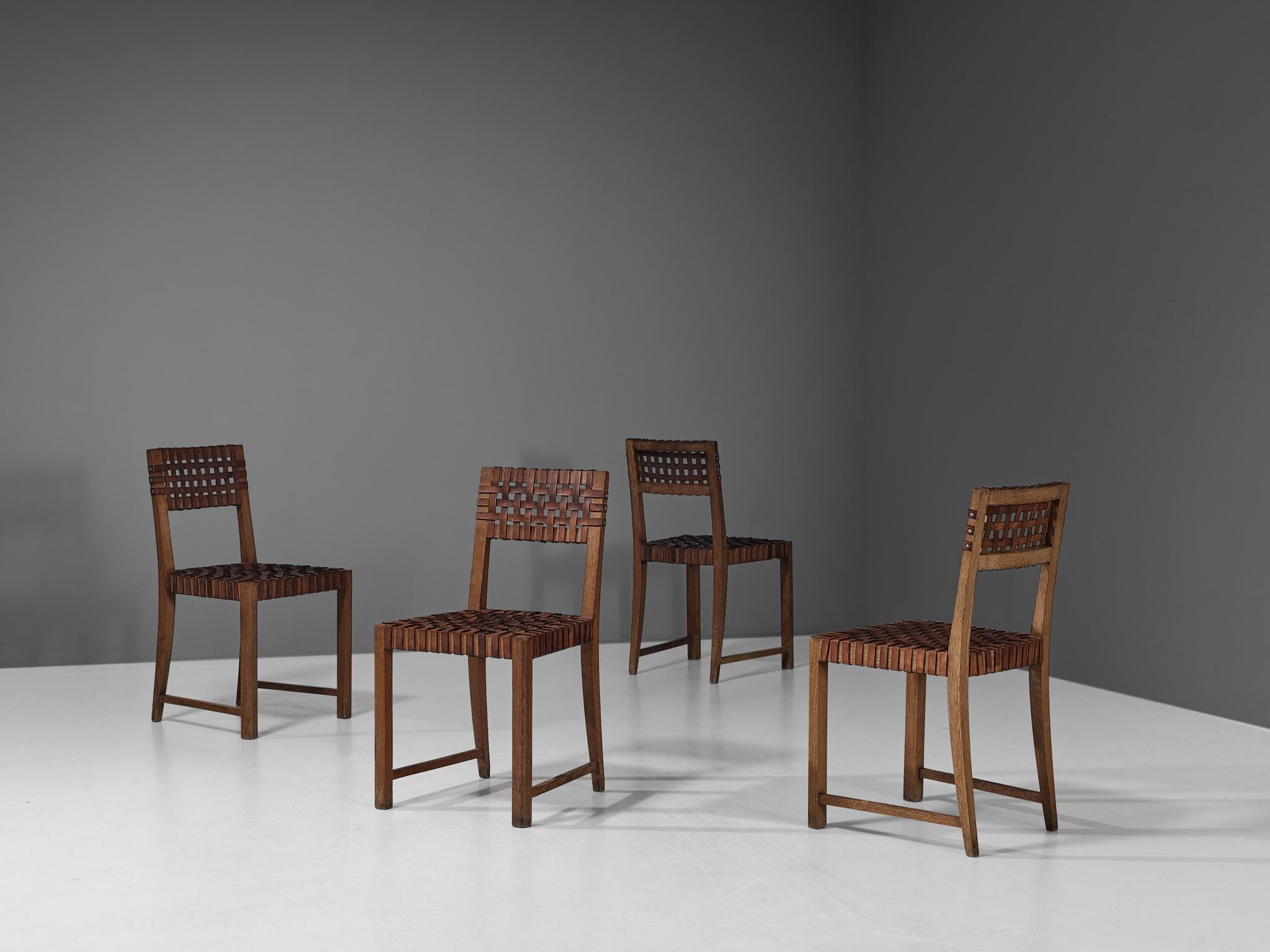 Set of four chairs, oak, leather, metal, France, 1950s. 

These robust chairs feature wonderful patinated leather on both seat and back. The patina creates a vibrant look and the straps in the seat form a thick, well-constructed yet aesthetically