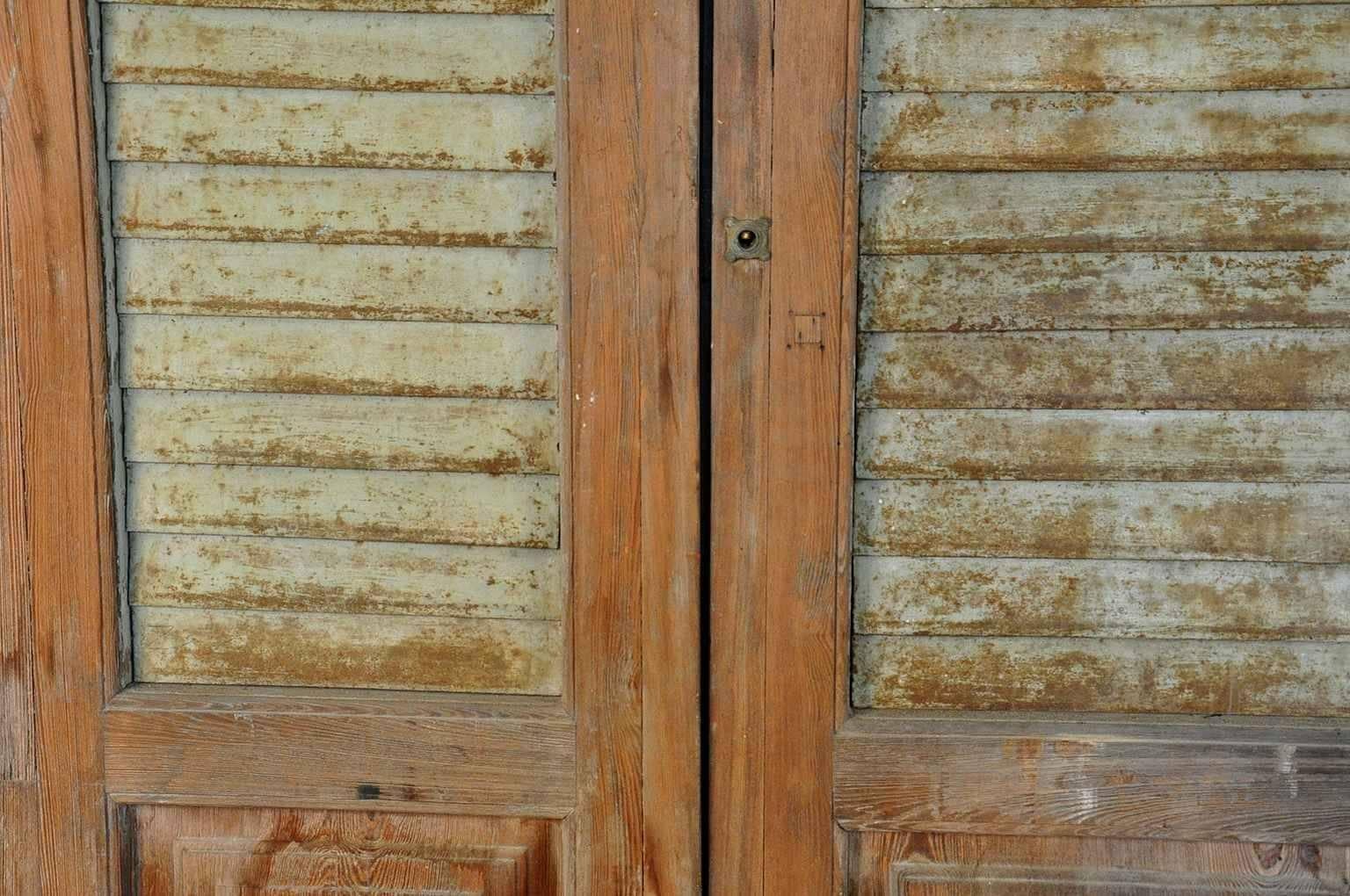 A terrific set of three washed, bleached wooden doors with painted metal louvered shutters. Wonderfully constructed with great patina. Not only fabulous built in, but would also serve beautifully as wall mounted art or headboard.