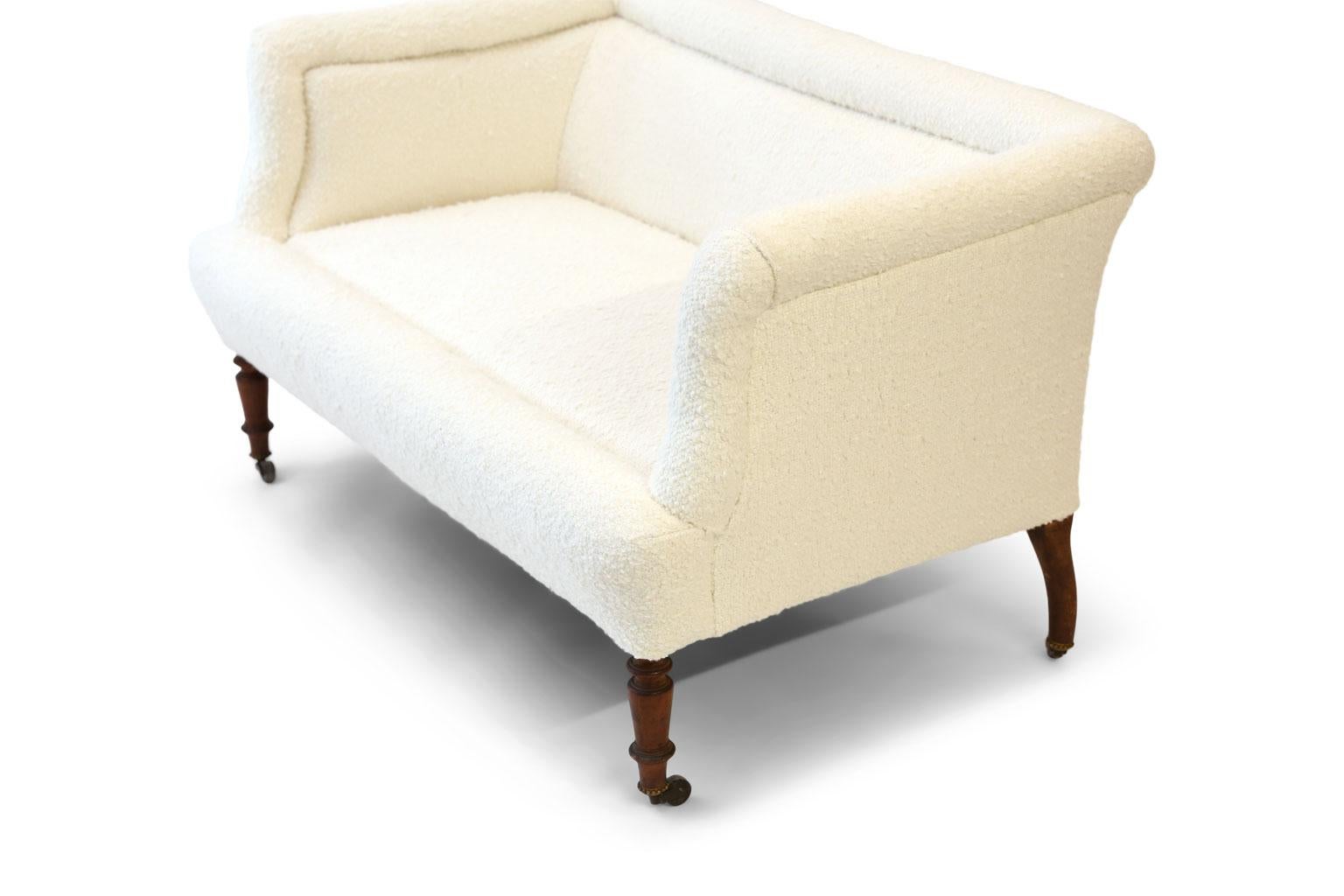 French settee upholstered in white wool bouclé. Pine frame resting upon casters. Constructed with pine frame, circa 1870-1890.