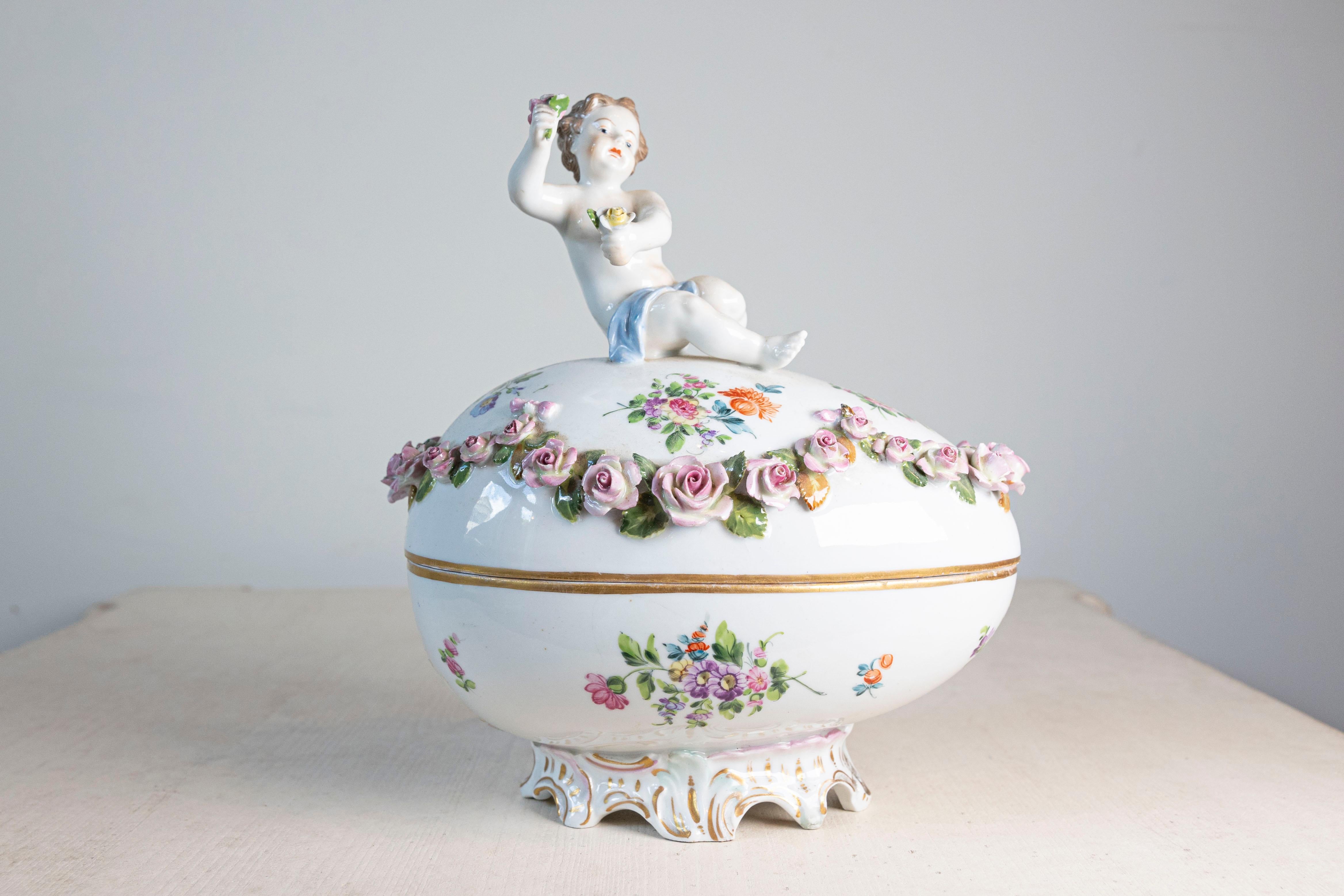 A French Sèvres Manufacture porcelain egg from the 19th century, with putto and floral hand painted décor. Born in France during the 19th century, this exquisite decorative egg features an oval lid beautifully adorned with a putto holding a delicate