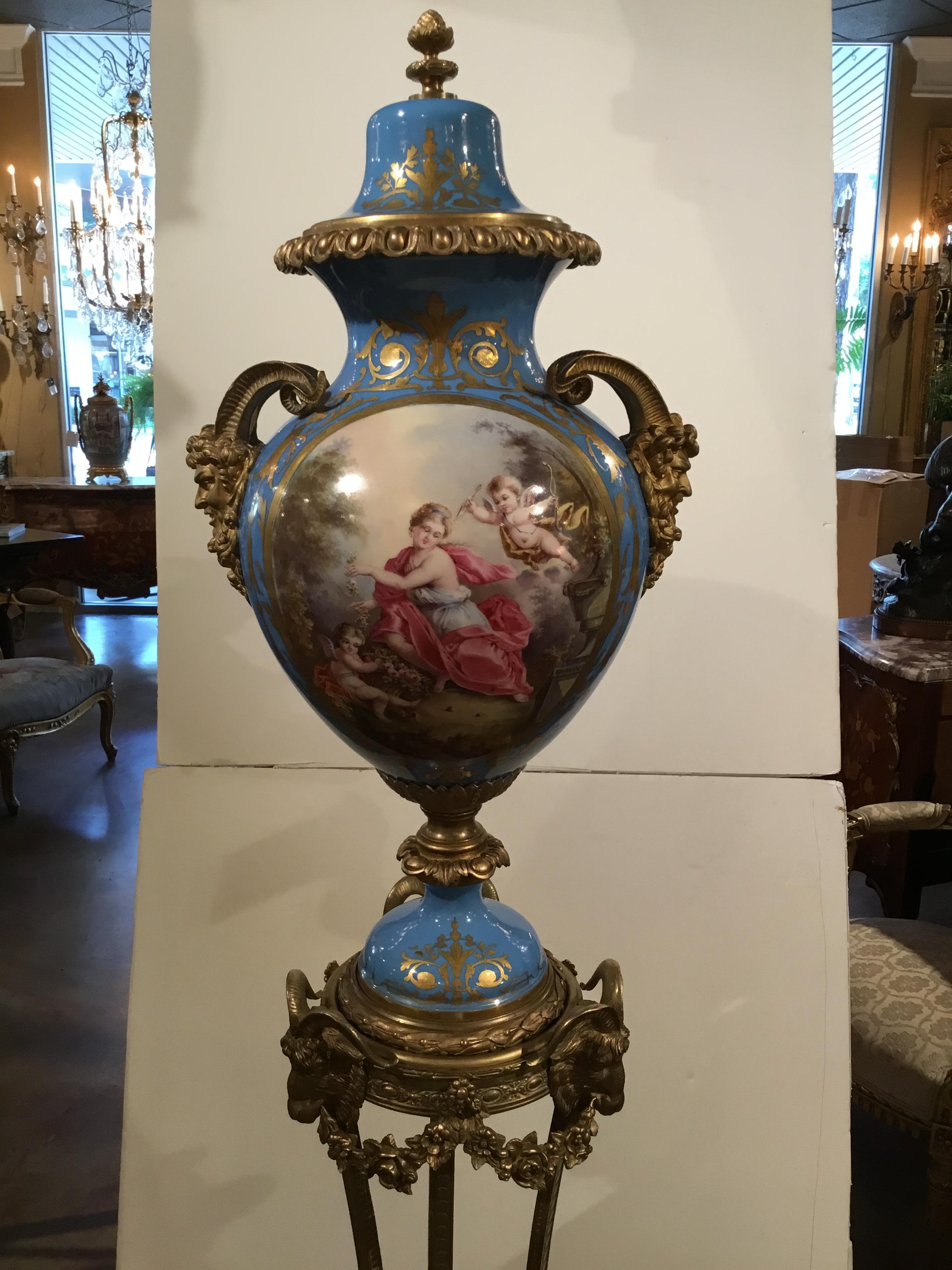 Sevres urn with French garden scene hand painted on the front of the urn
And a French landscape painted on the verso. Sevres mark is painted
Under glaze in the cap of the urn. It is mounted in a bronze doré pedestal
With rams heads mounted on the