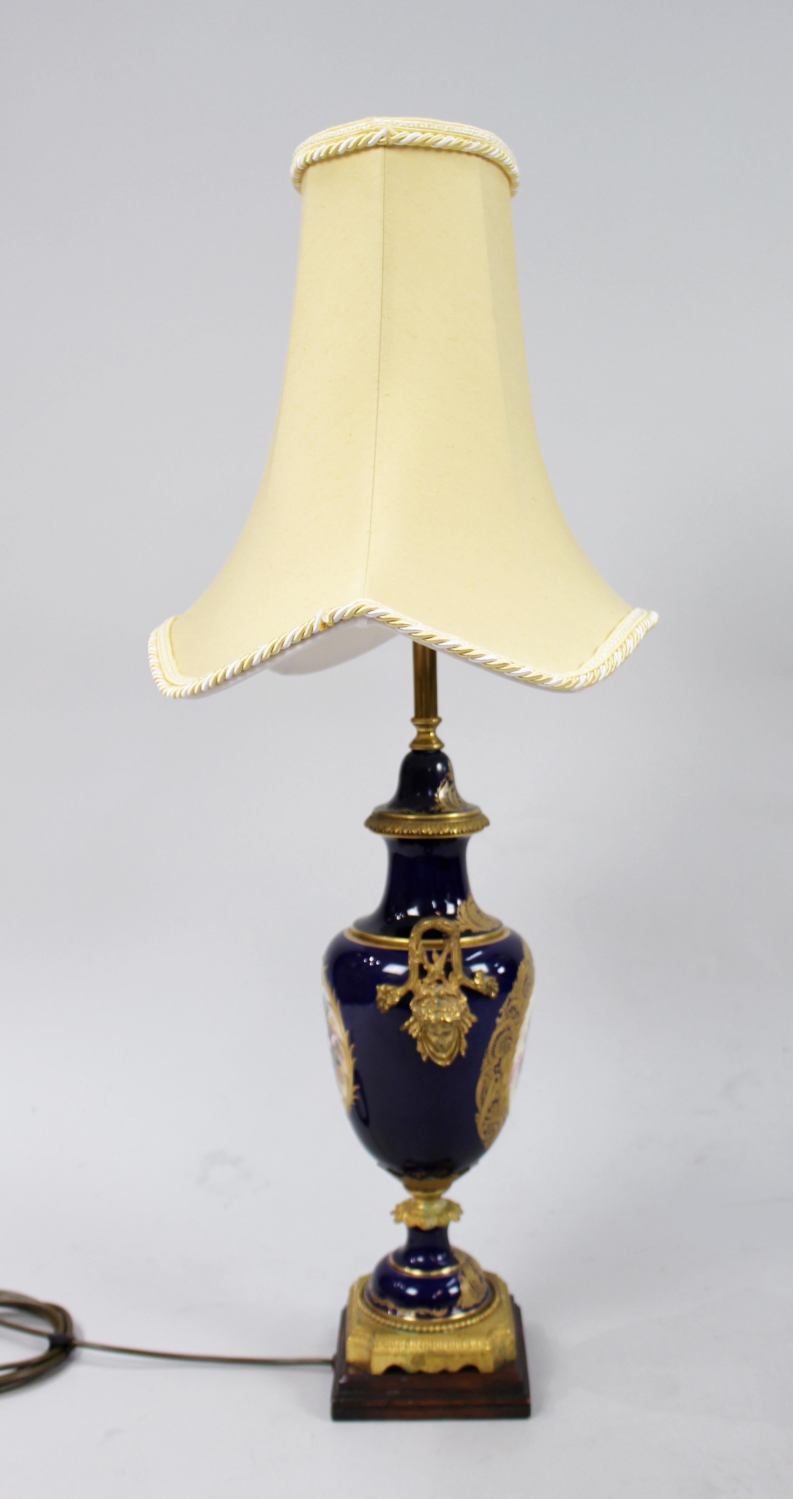 Period 
Mid-late 20th century, French

Lamp 
Porcelain body with rich cobalt blue ground. Decorative panels to front and back; cherubs and flowers. Gilded cartouche surrounds to both, heavily gilded to the whole. Brass lamp fitting. Ormolu
